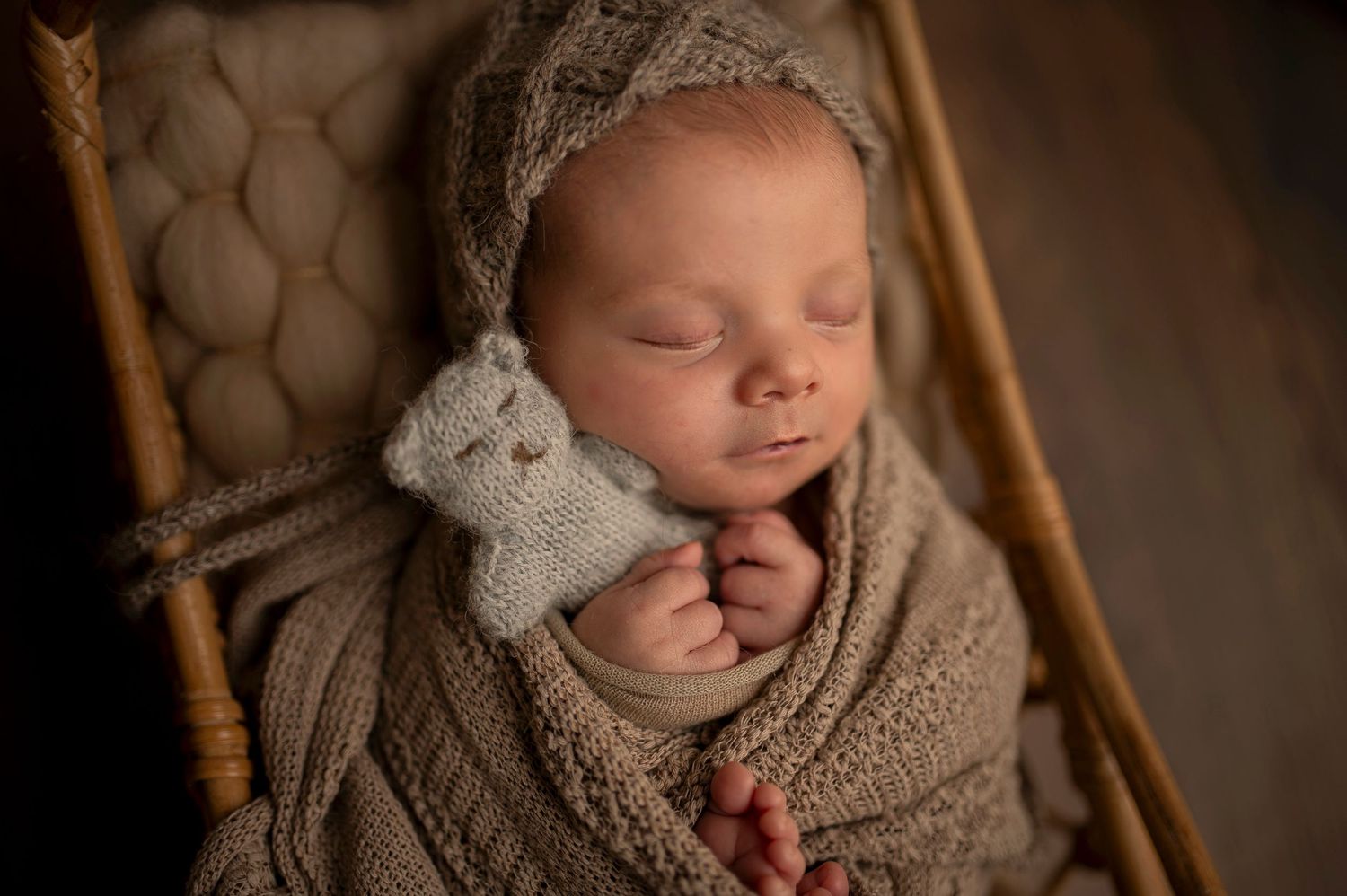 Peaceful sleeping newborn with stuffed toy in vintage wicker basket.