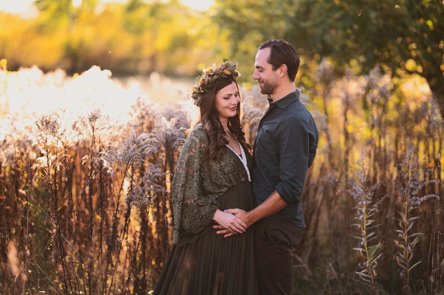 Couple embracing in autumn field with golden light filtering through.