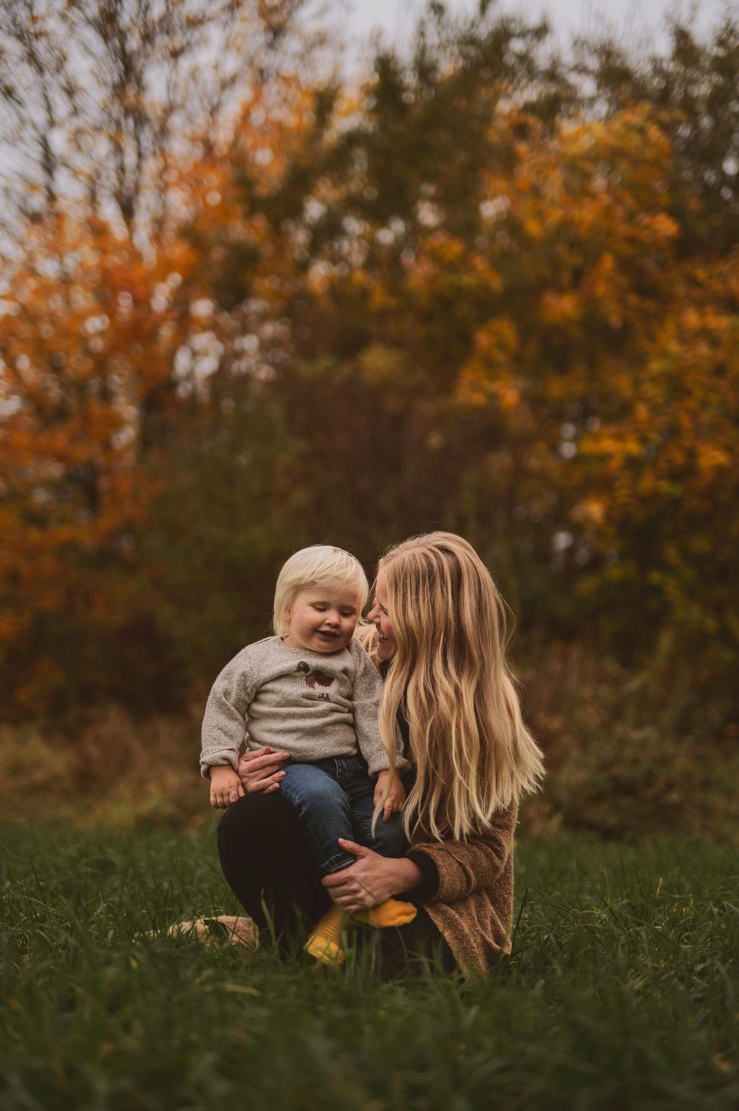 Warm autumn scene in a grassy field with falling leaves and cozy knit sweaters.