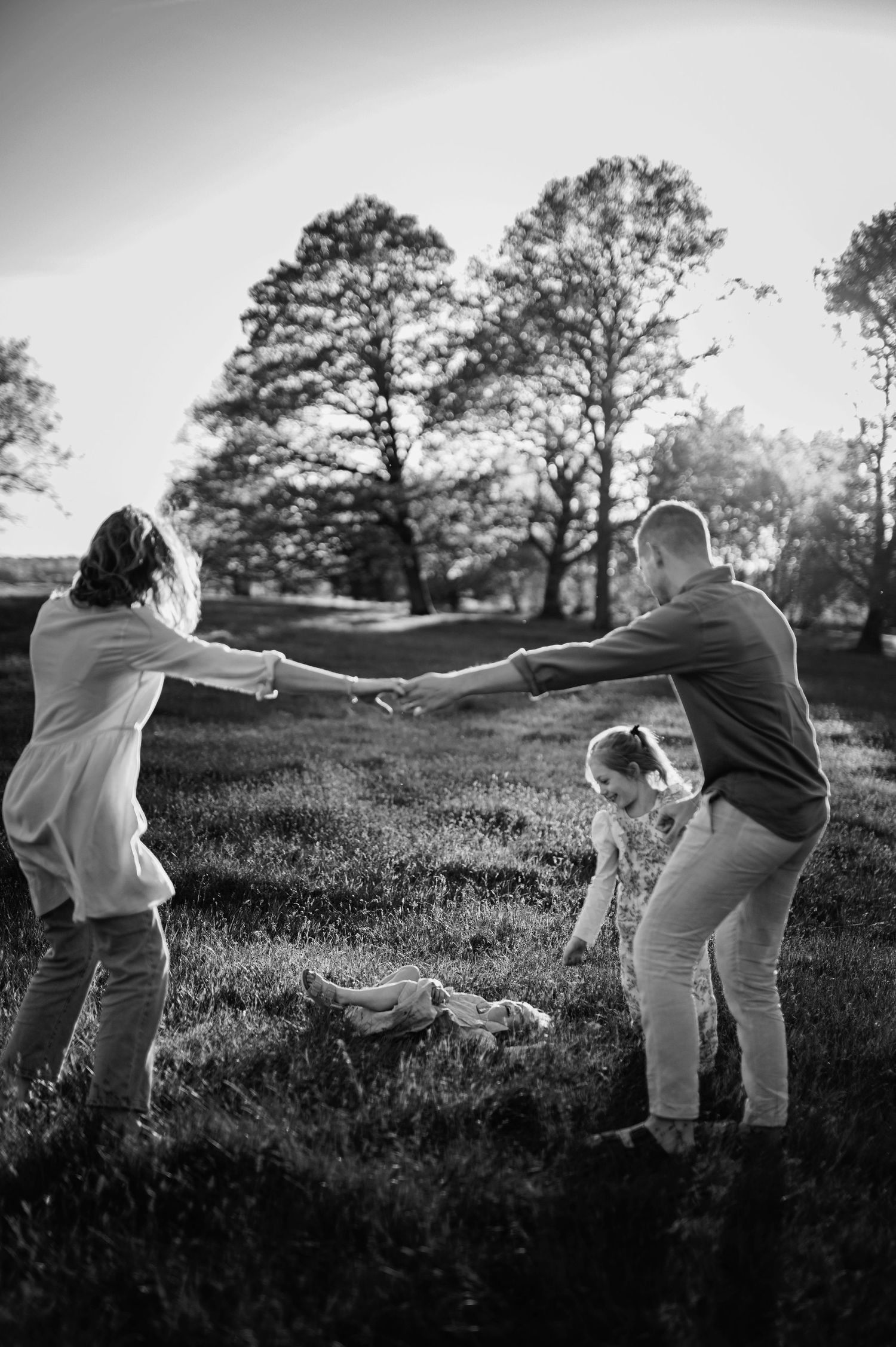 Family playing together in field during sunset while holding hands in circle.