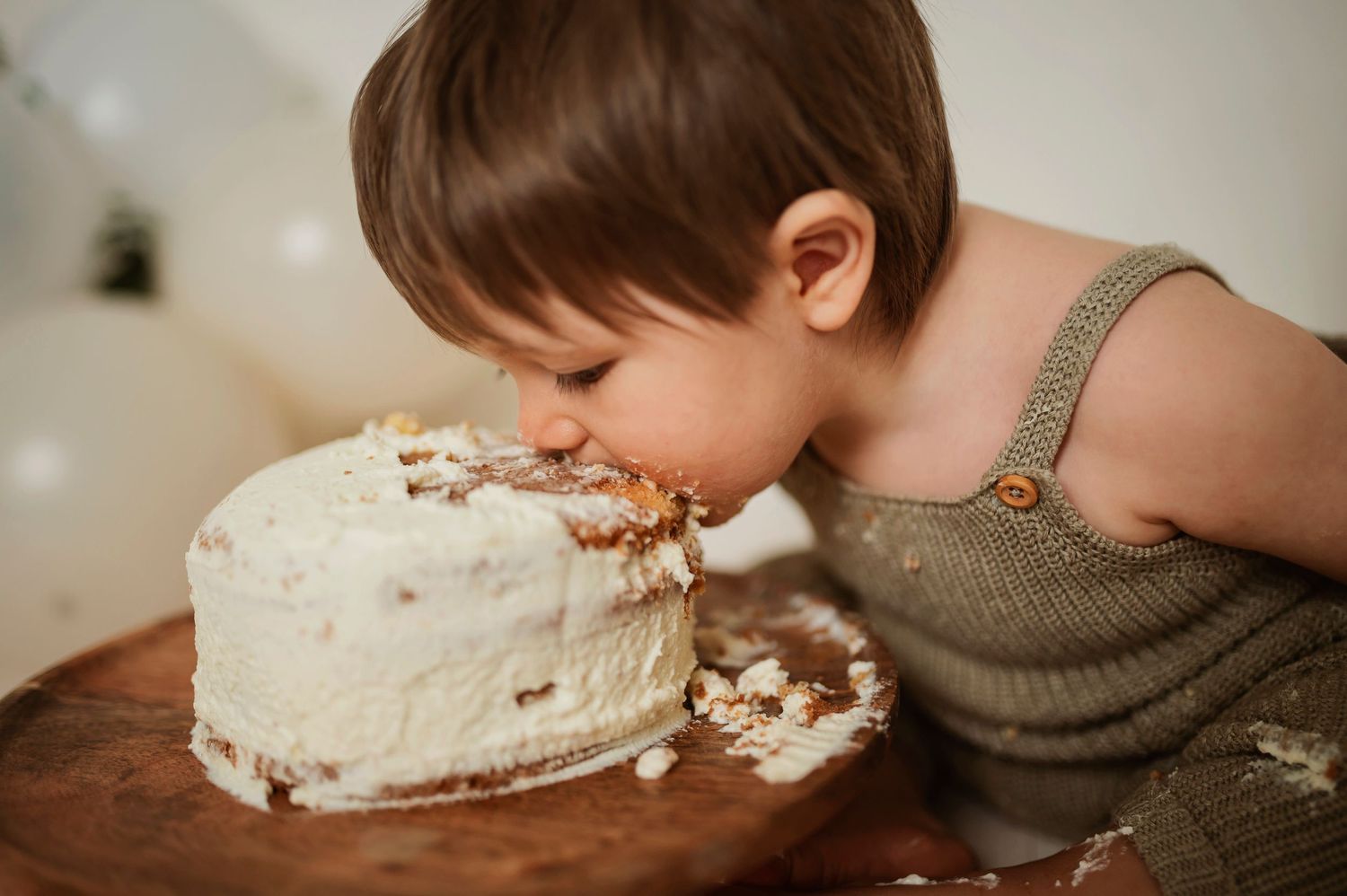A person takes a bite of a creamy white dessert while seated at a wooden table.