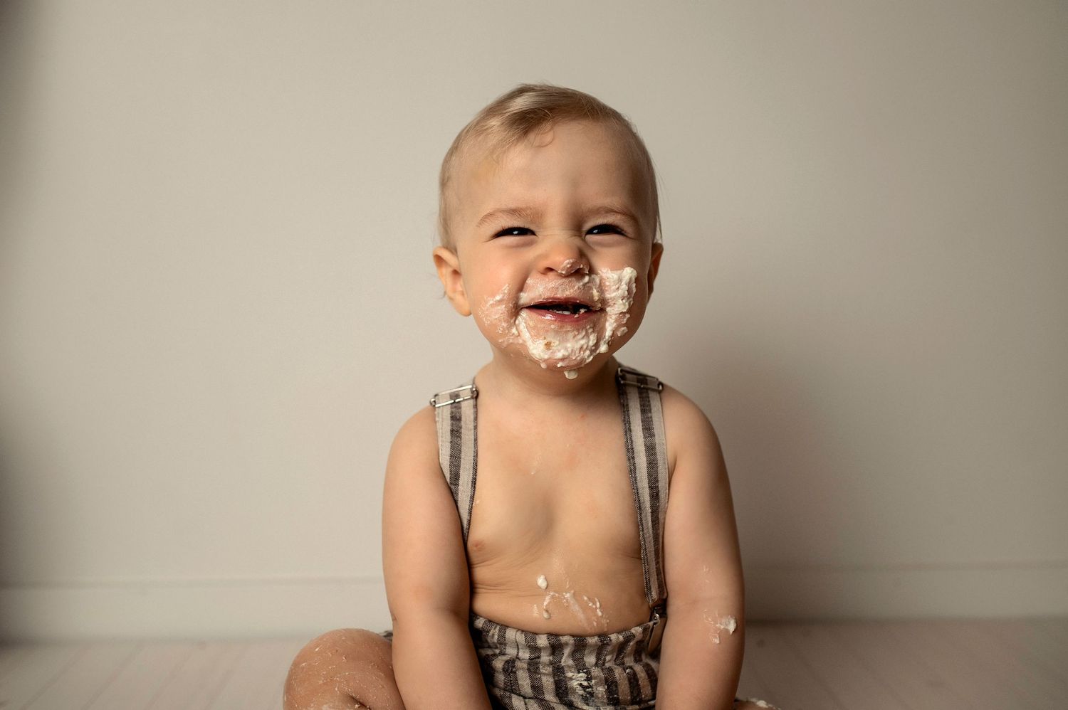 A series of candid photos showing a baby laughing and playing while sitting on a neutral colored background.