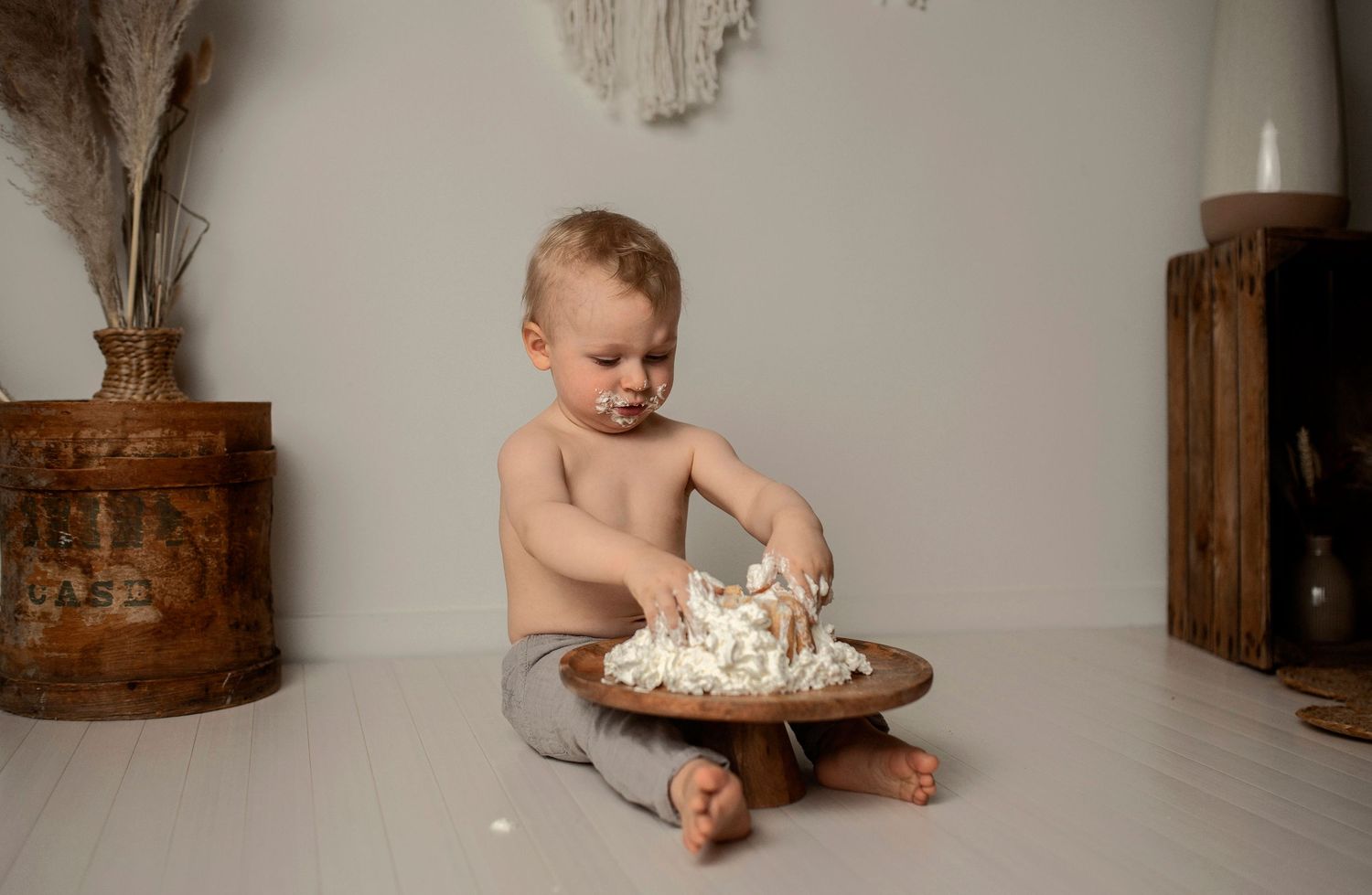 A series of five connected photos showing a baby's first birthday cake smash photoshoot against a white backdrop.
