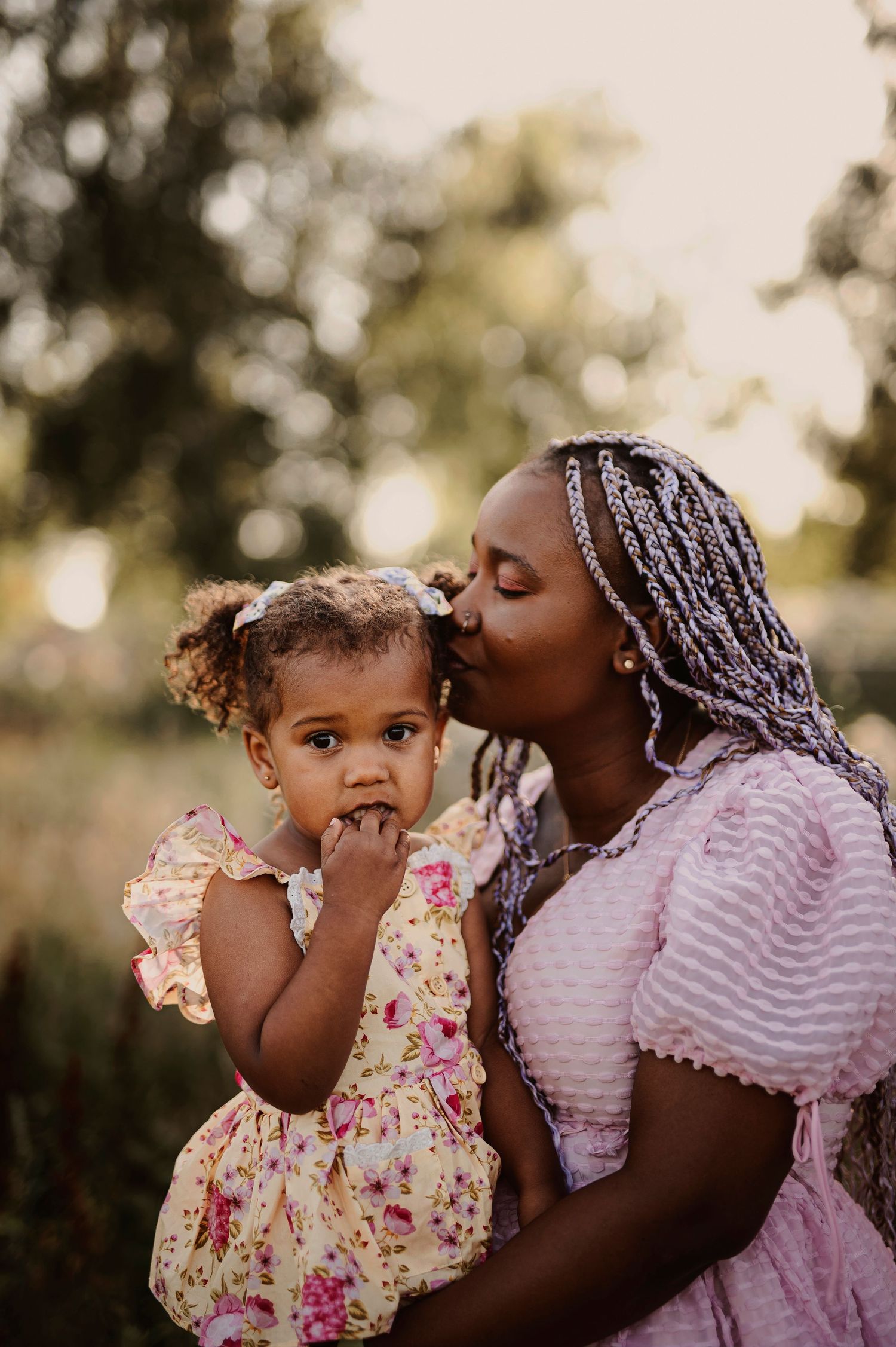 A tender moment captured between parent and child in matching pink outfits outdoors.
