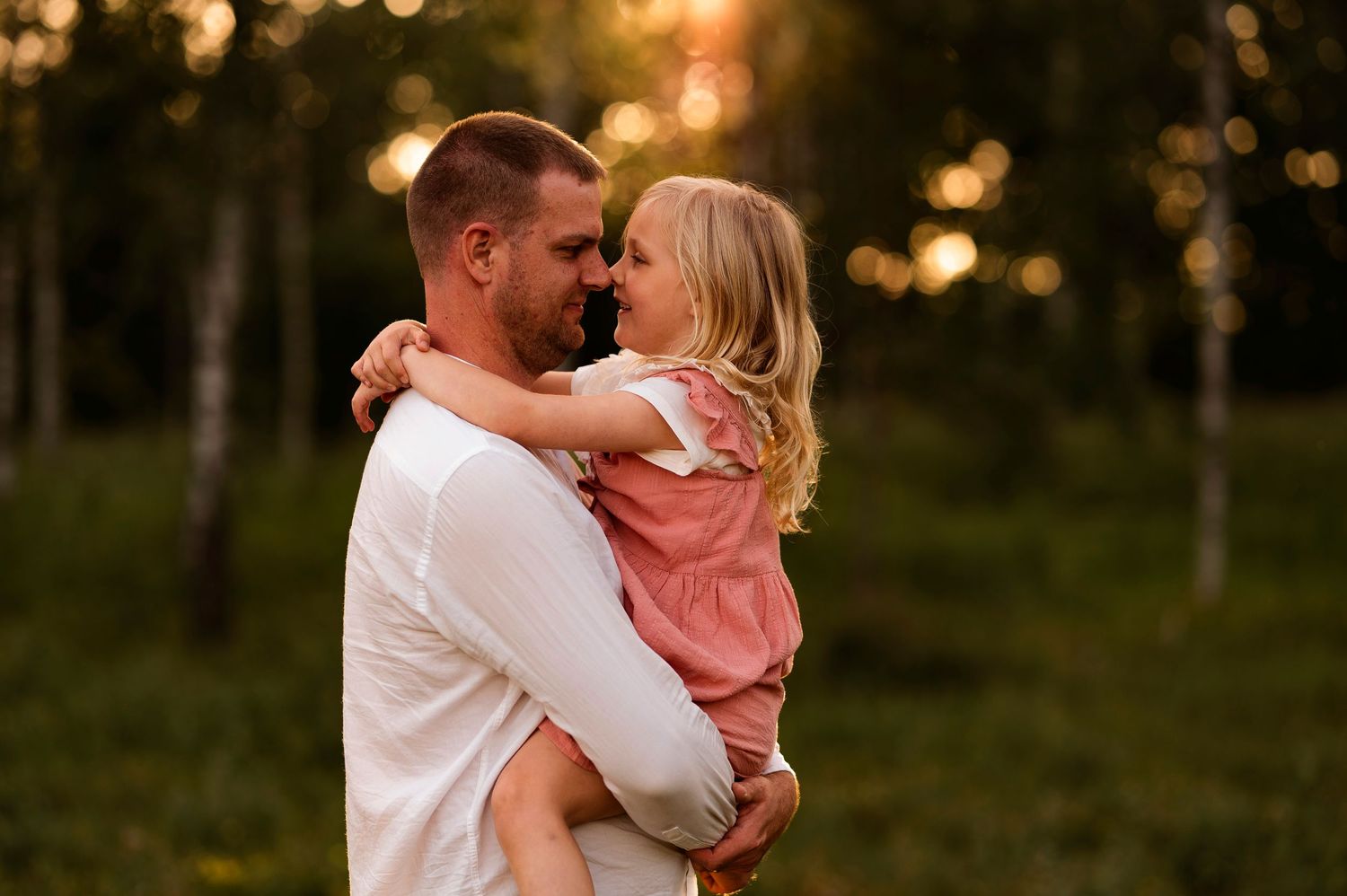 A tender embrace captured at sunset in a wooded field.