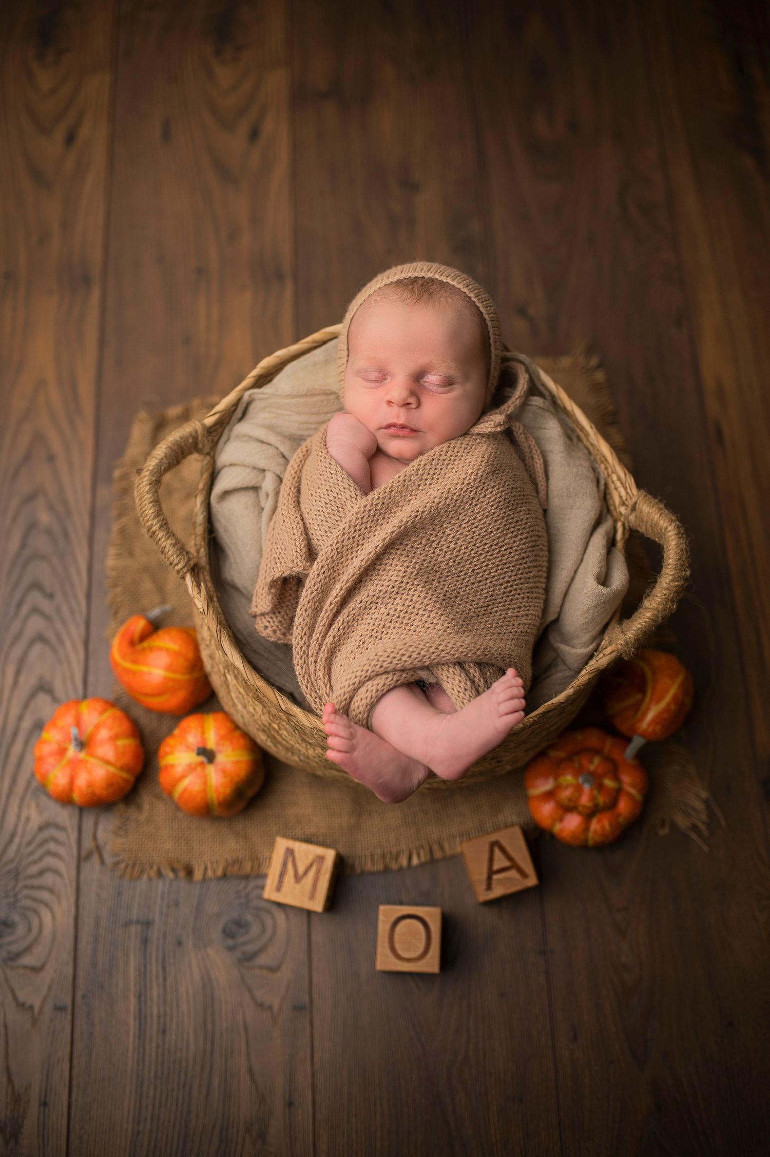 Nyfödd på nyföddfotografering hos Lovestories By Sara. Bebisen ligger i en korg och där är pumpor som rekvisita.