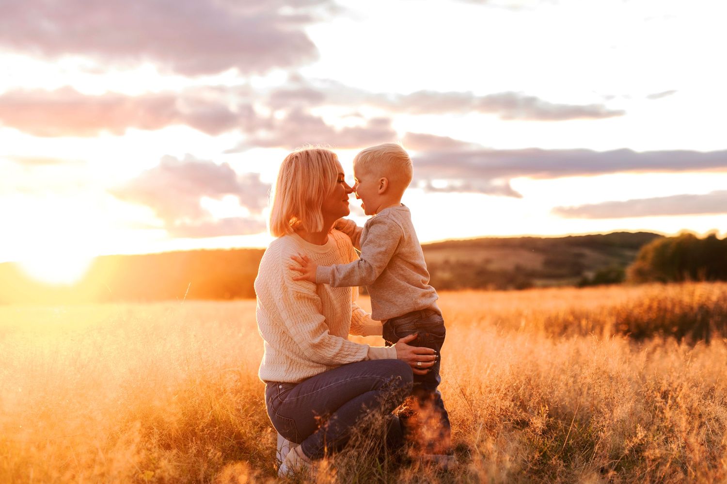 Sweet interaction between parent and child in a golden wheat field at sunset.