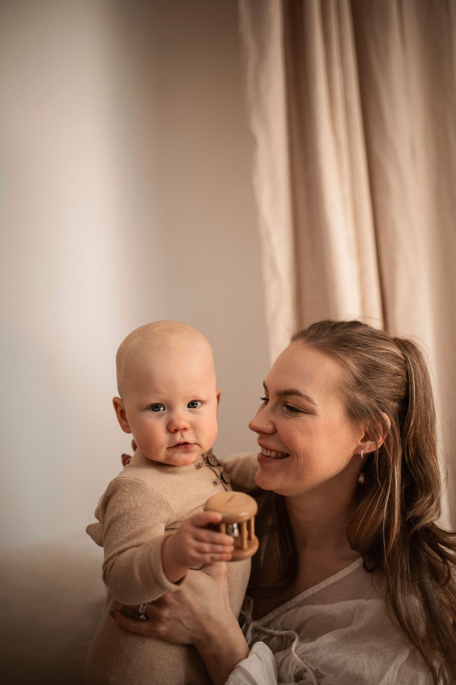 A mother holding and lovingly interacting with her baby in a series of tender moments against a soft neutral background.