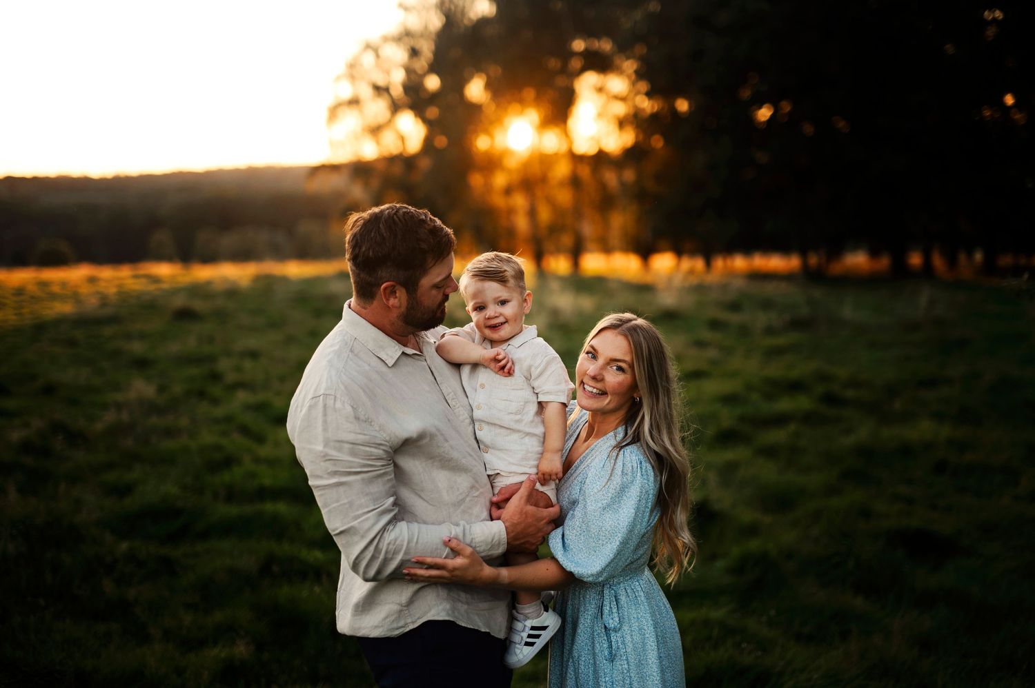 Family sharing joyful moment together in field during golden sunset.