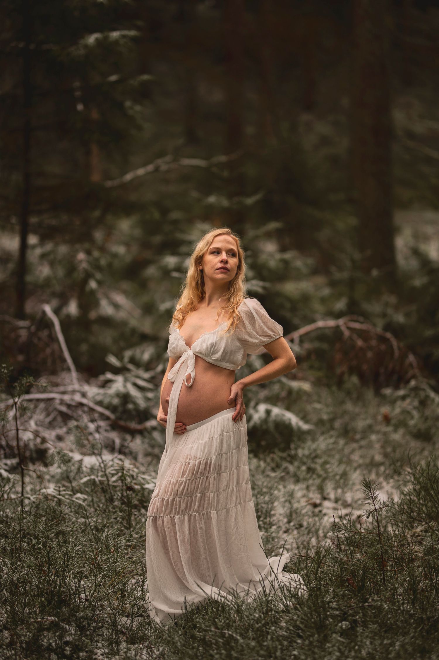 Vacker gravid kvinna på fotografering i en skog med mossa. Fotograf är Lovestories By Sara.