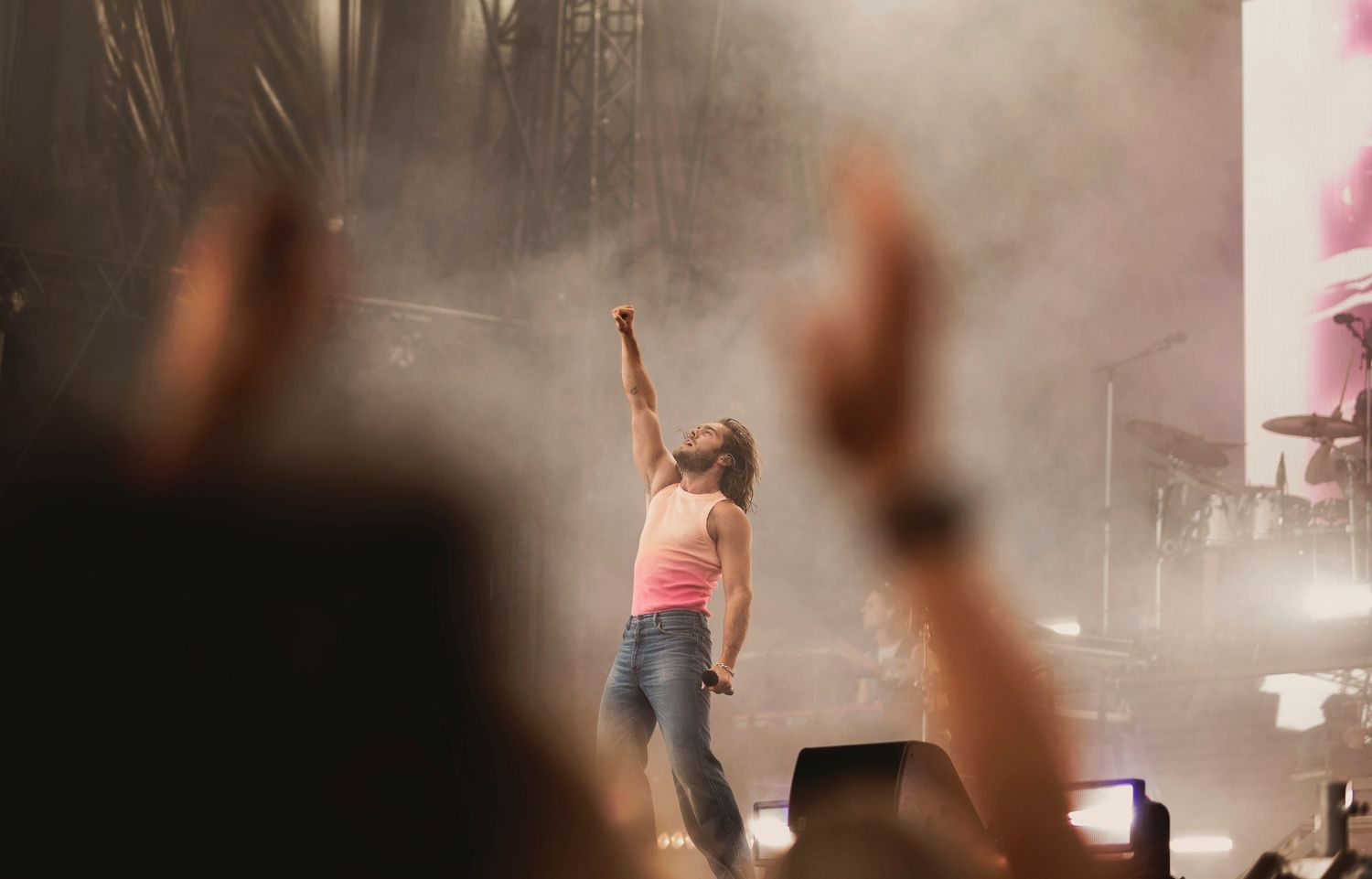 Female performer on stage raising fist to crowd in smoky concert atmosphere.