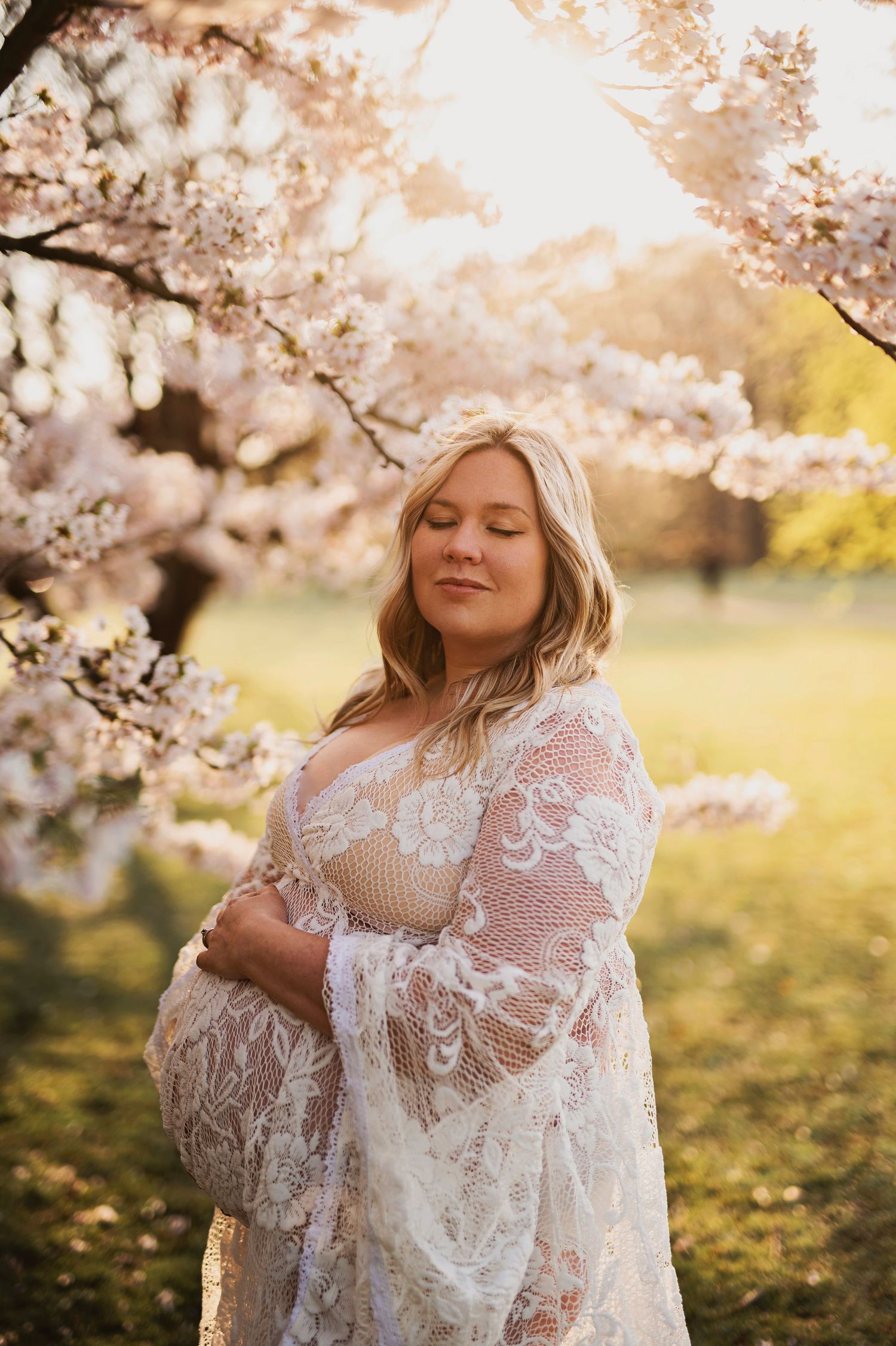Vacker gravid på fotografering bland körsbärsträd fotograferade av Lovestories By Sara