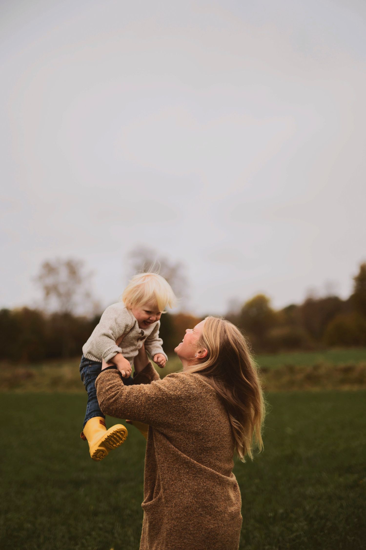 Playful interaction between figures in a field with fall foliage in the background.