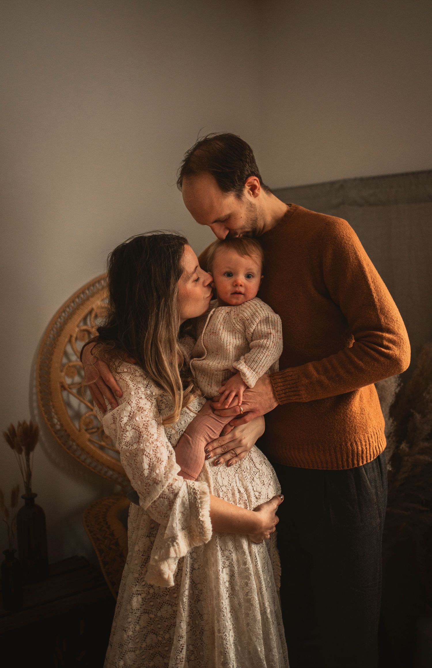Intimate family portrait in warm tones featuring cozy knit sweaters and vintage decor.