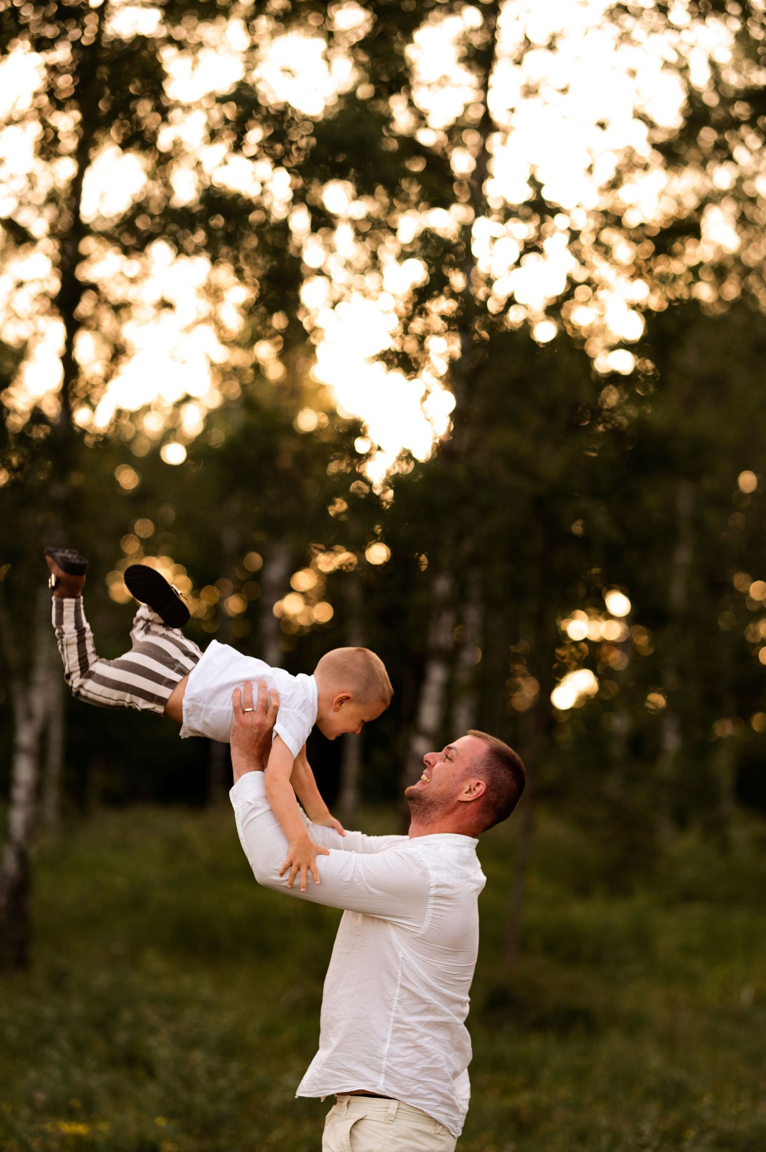 Playful moment captured as a figure lifts a child high in the air during sunset.