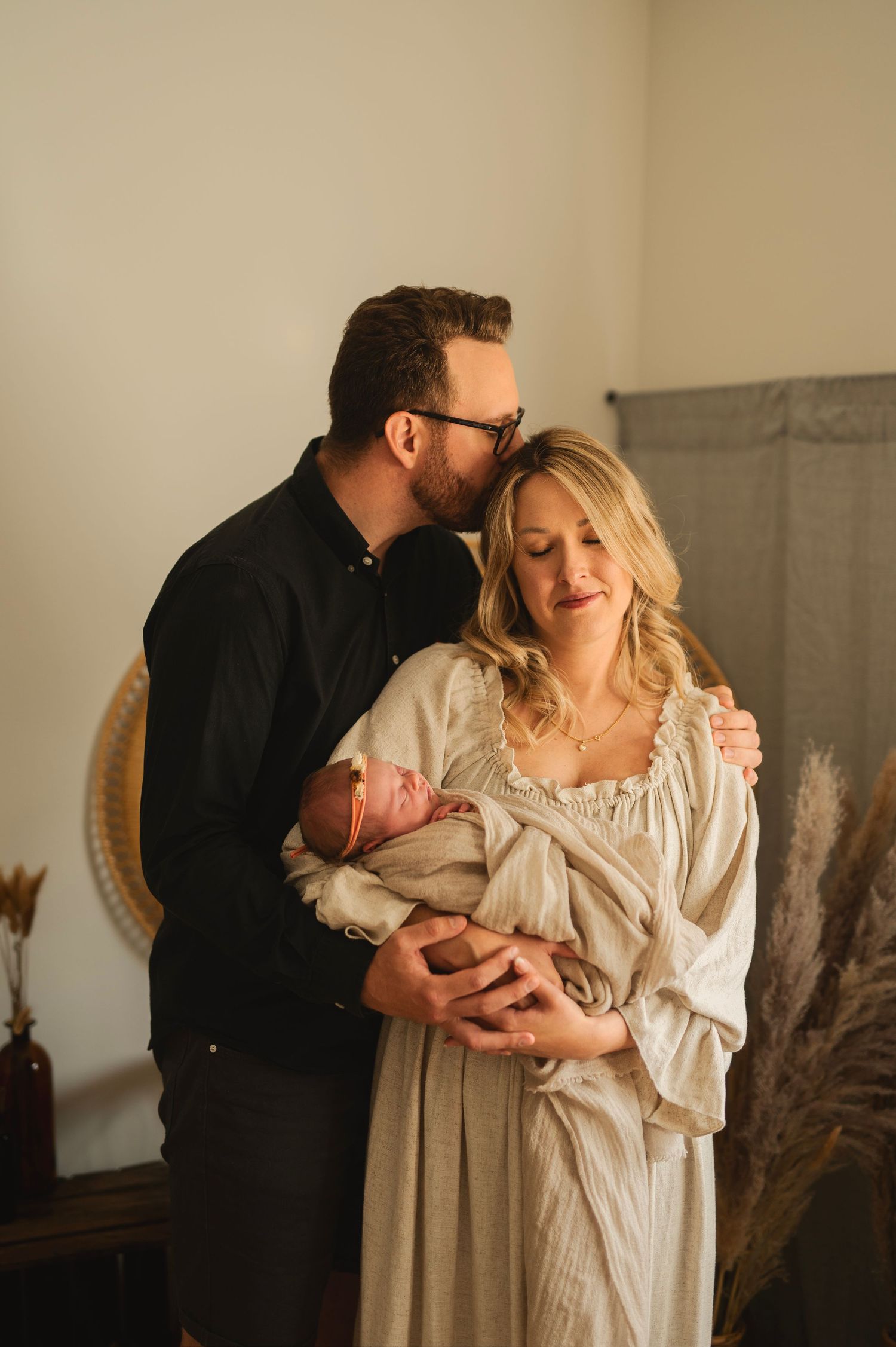 Indoor family portrait with newborn in rustic setting with dried pampas grass decor.