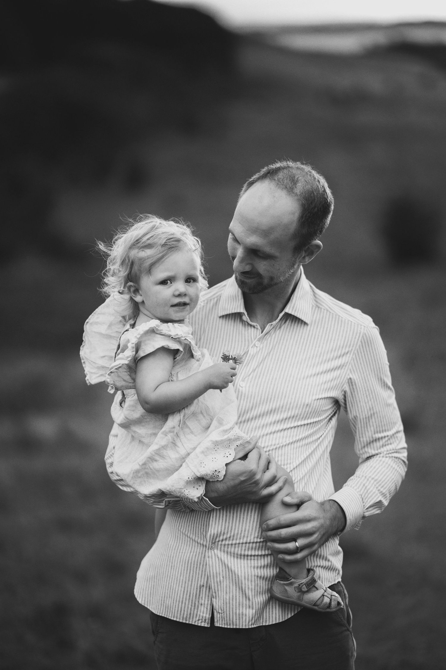 Parent and child sharing tender moment against rural hillside backdrop.
