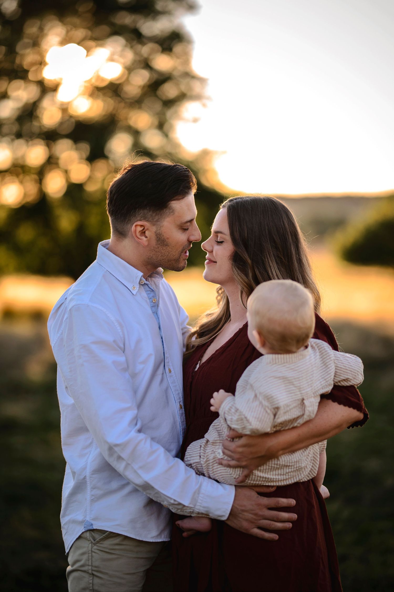 Intimate family moment captured during golden hour in natural outdoor setting.