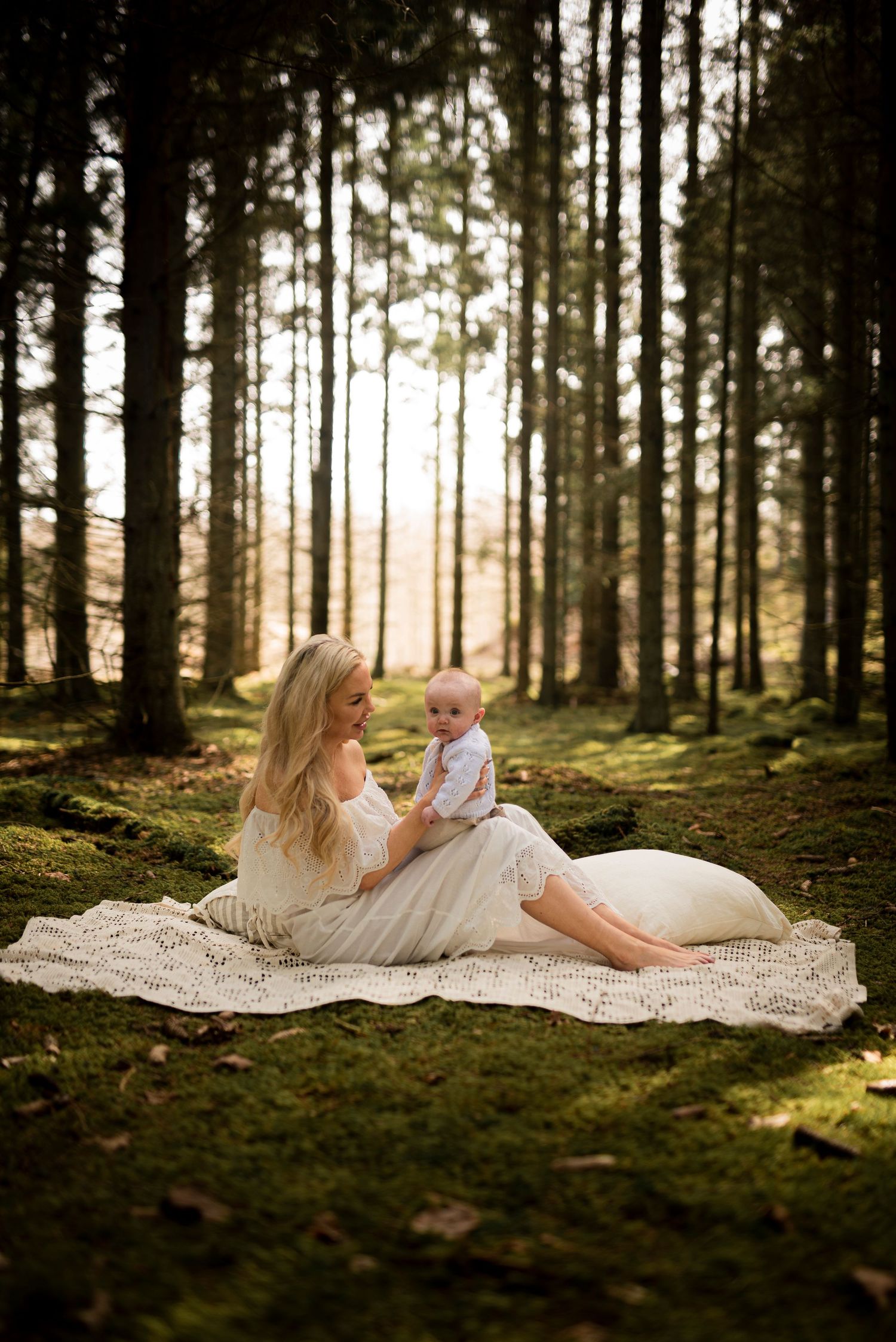 An intimate family portrait set in a magical forest setting with dappled sunlight.