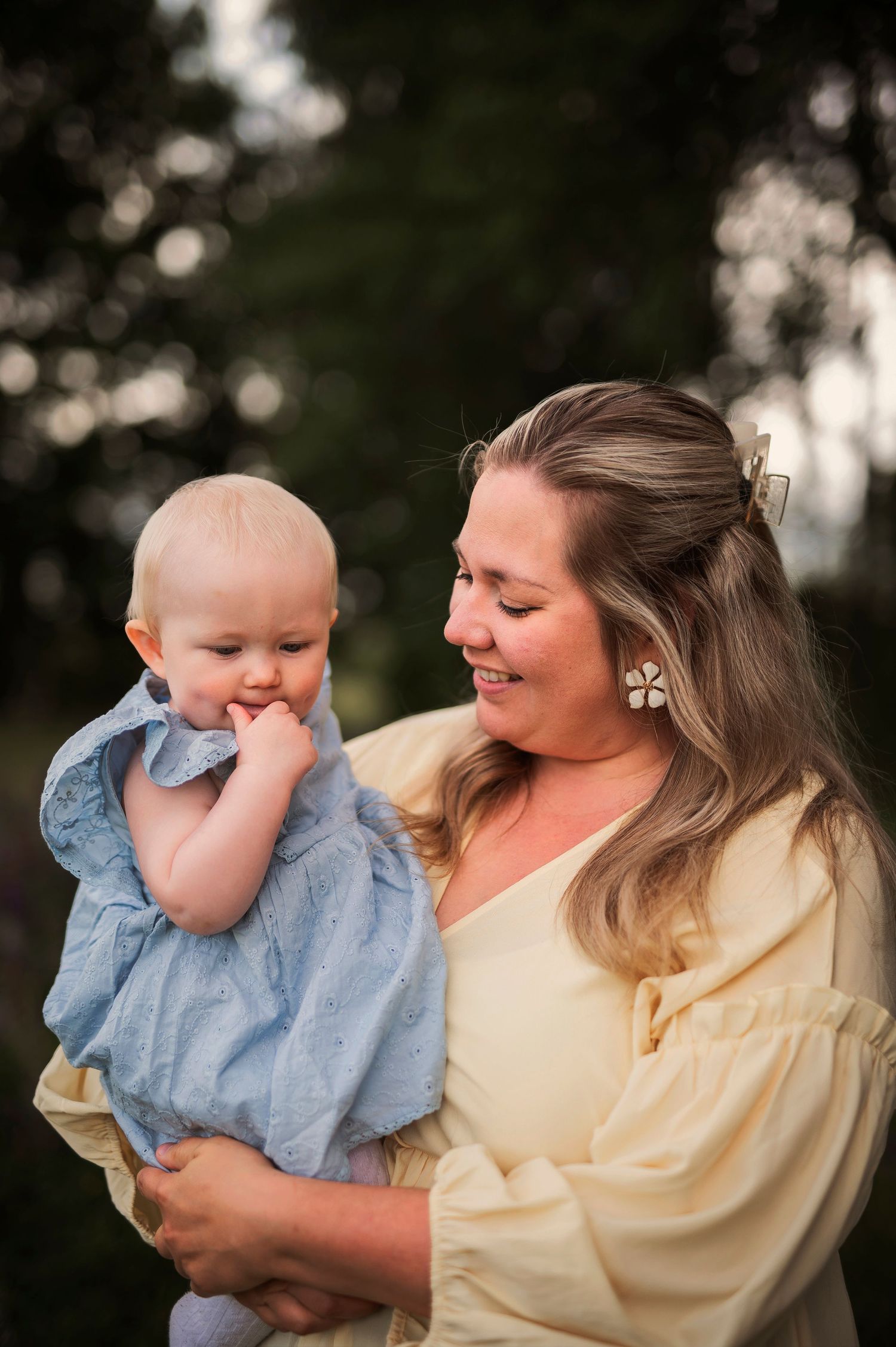 A sweet candid moment between parent and baby in matching cream and blue outfits outdoors.