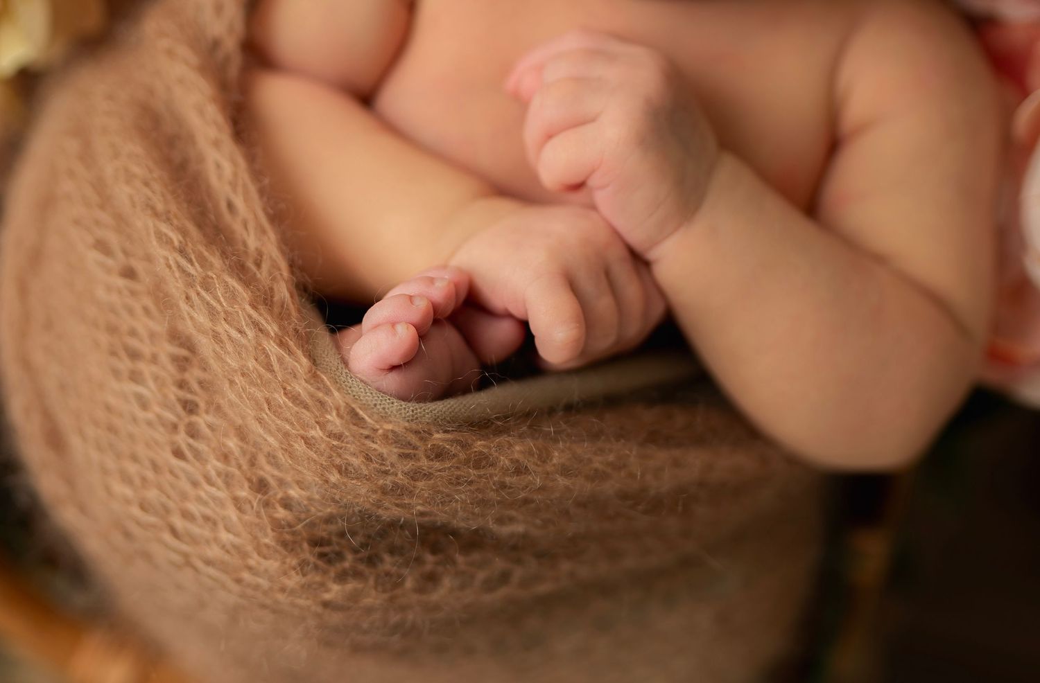 Close-up of tiny baby hands and fingers against soft knitted fabric.