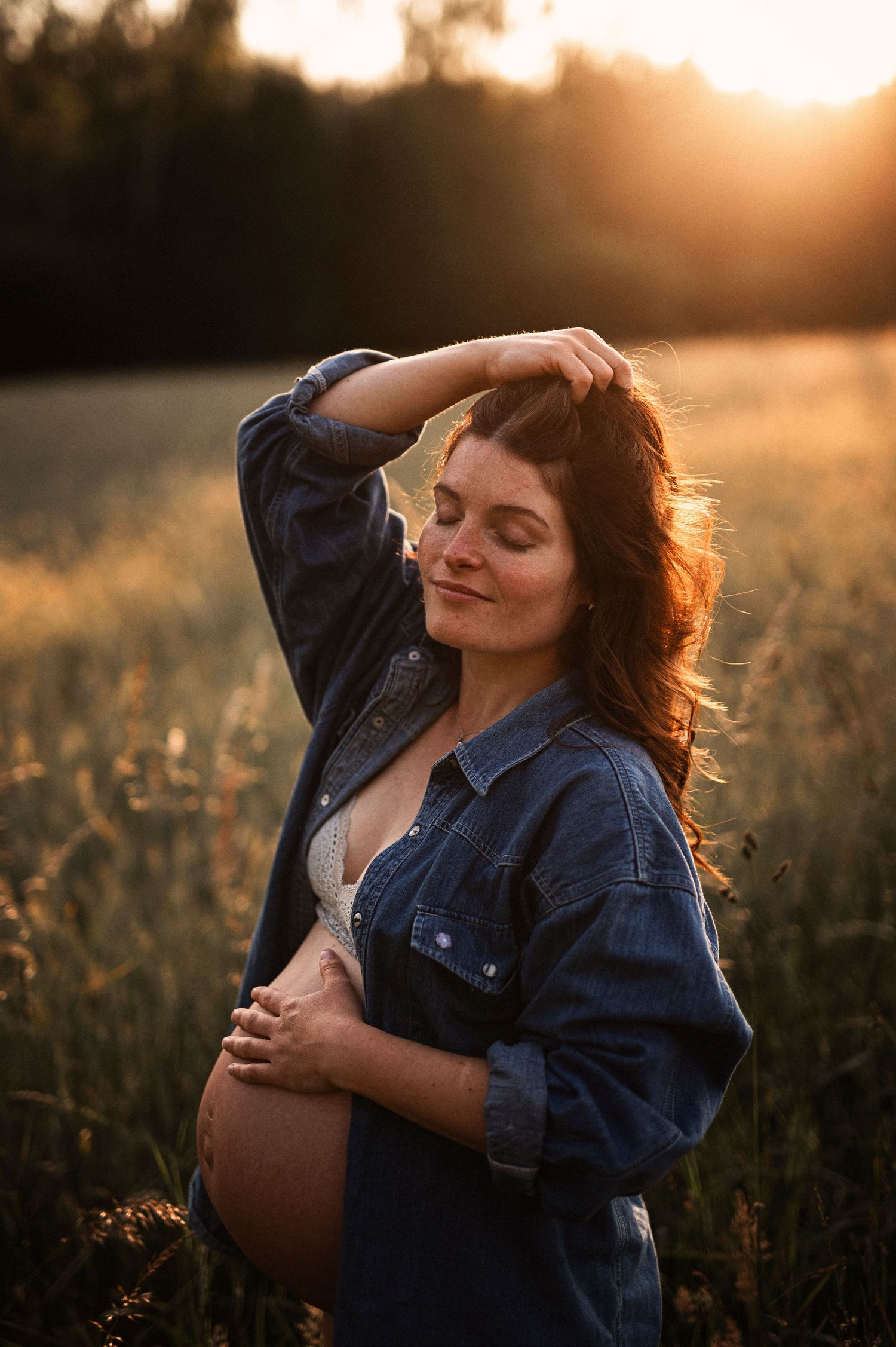 A peaceful maternity portrait captures a serene moment in a sunlit meadow.