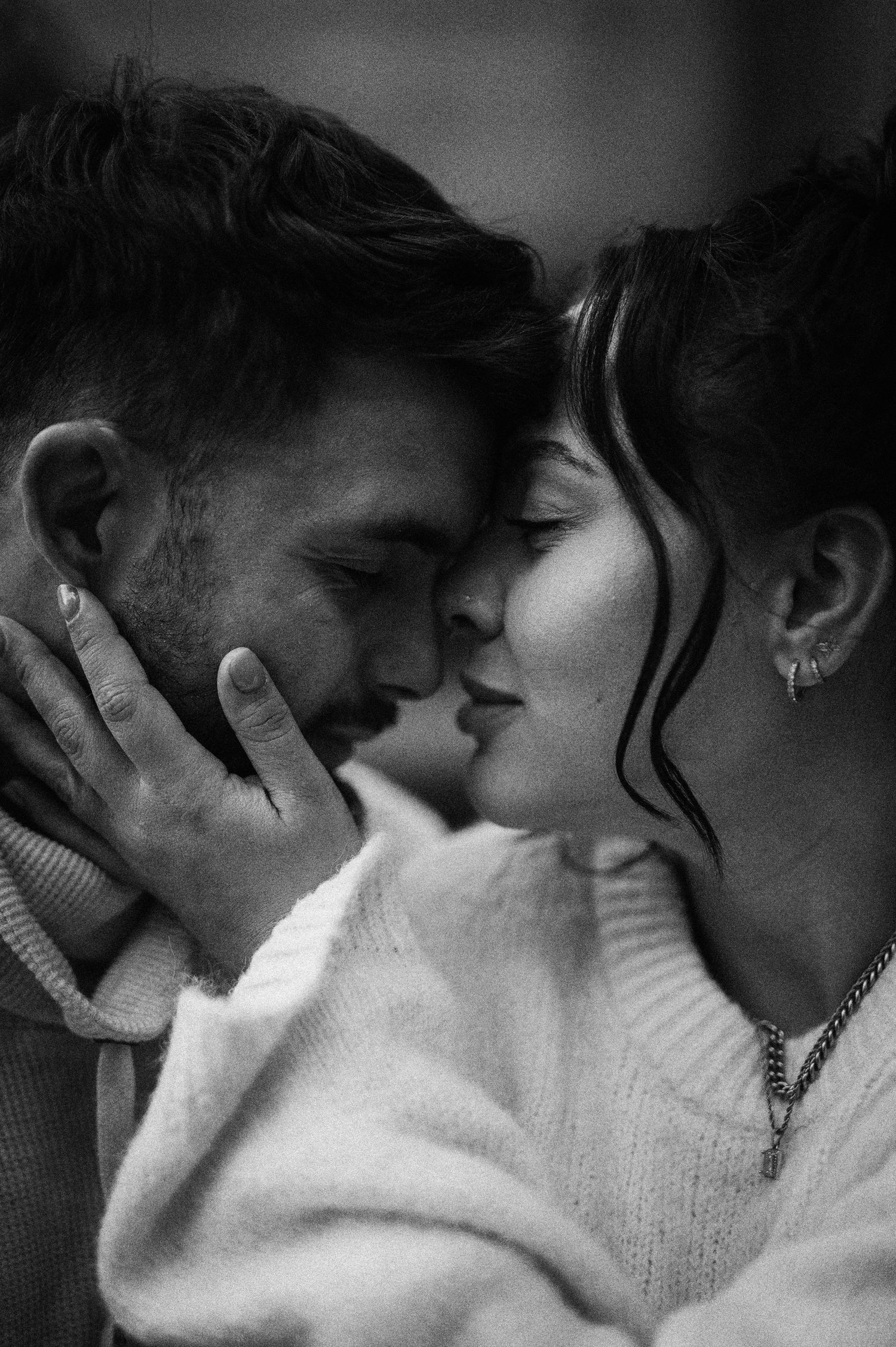 Intimate black and white portrait of couple sharing a tender moment in sweaters.