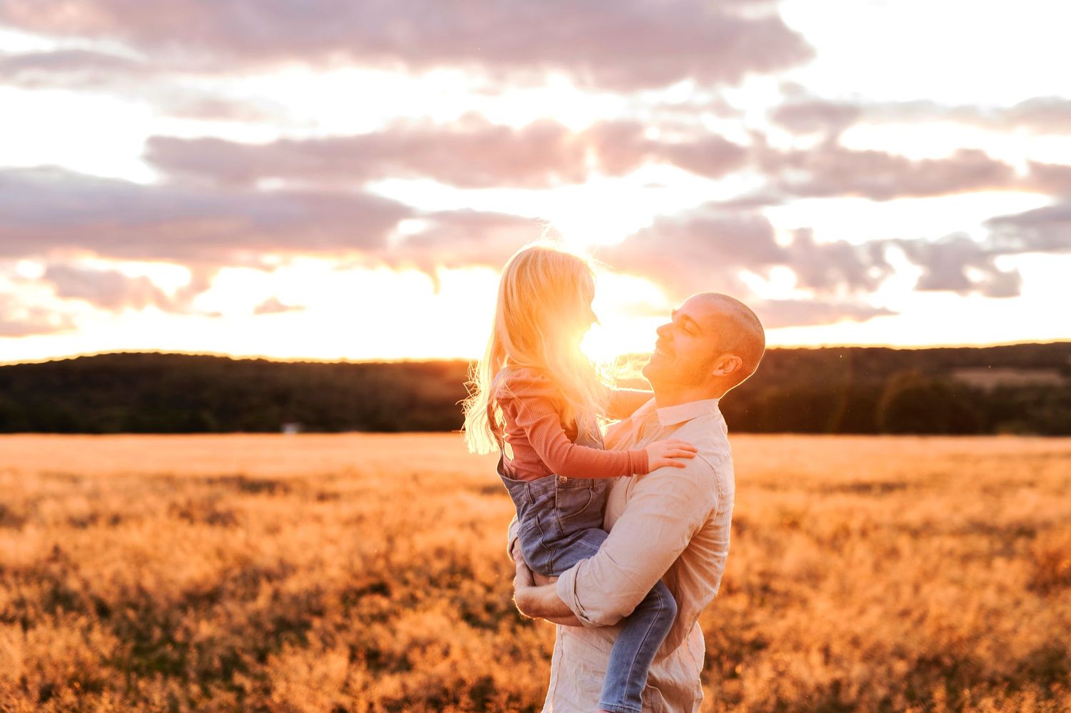 Silhouette of embracing figures against a dramatic sunset in a golden field.