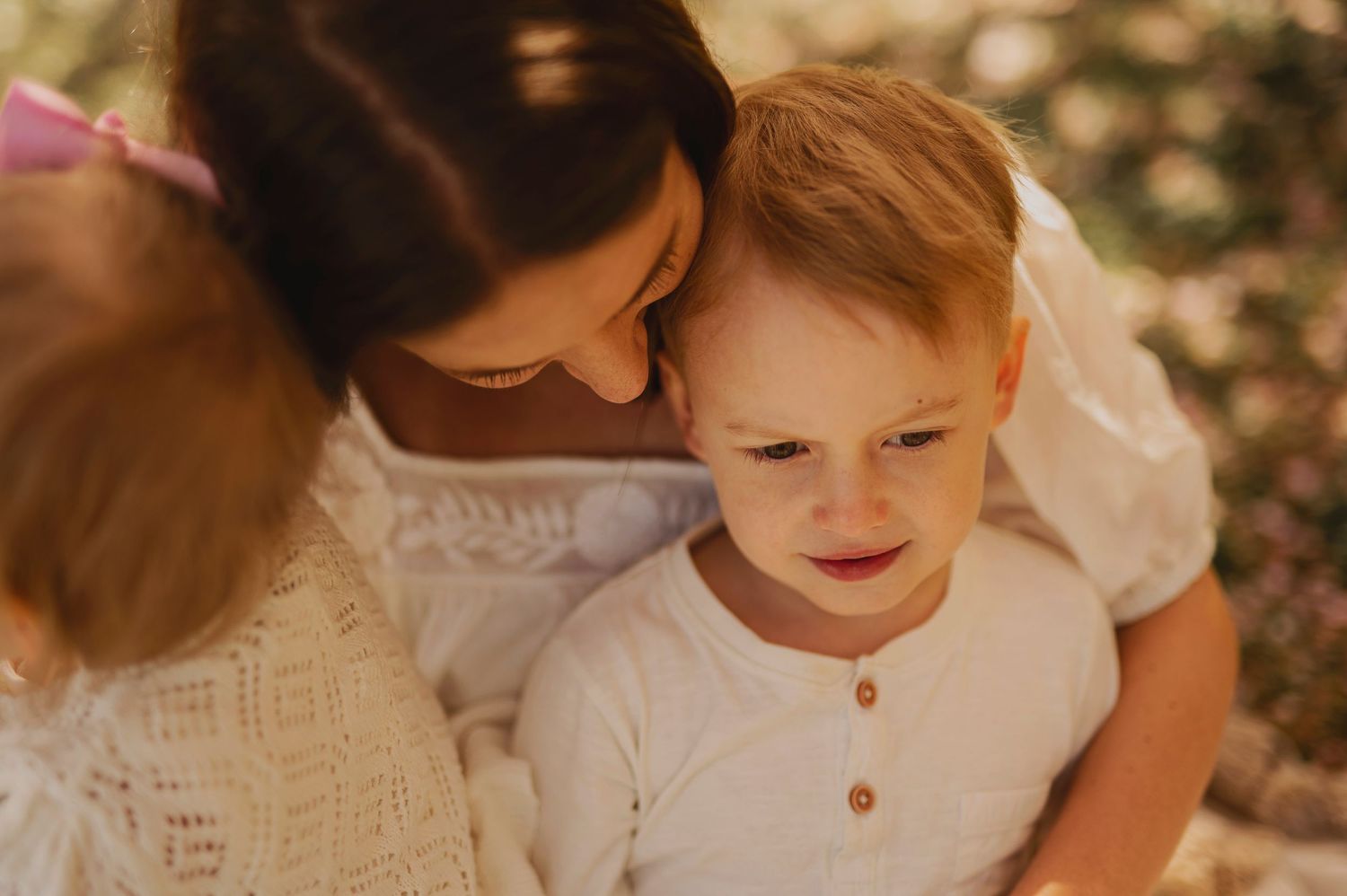 A tender embrace in white clothing against a soft bokeh background.