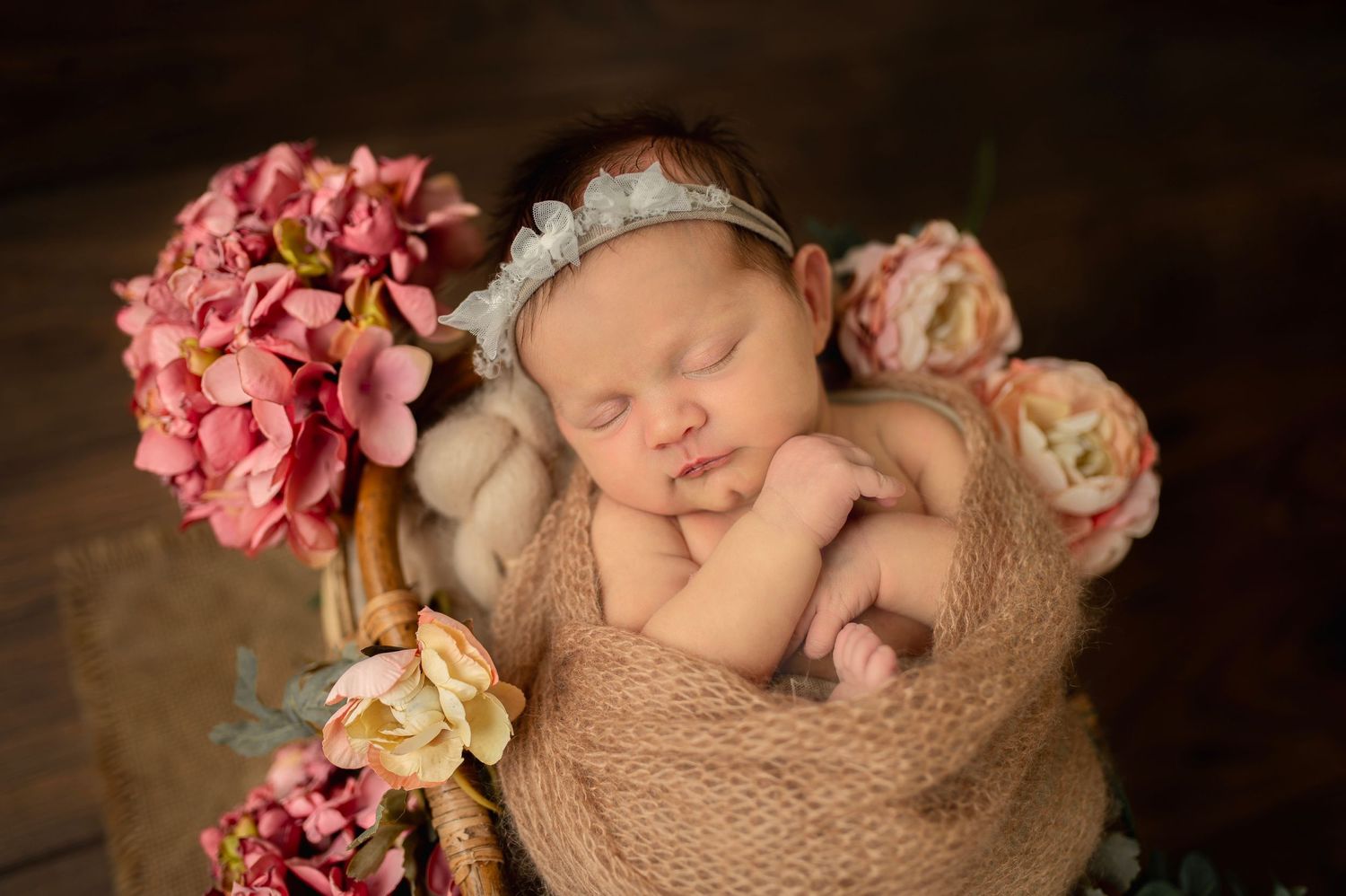 Peaceful newborn portrait with vintage roses and soft beige wrapping.