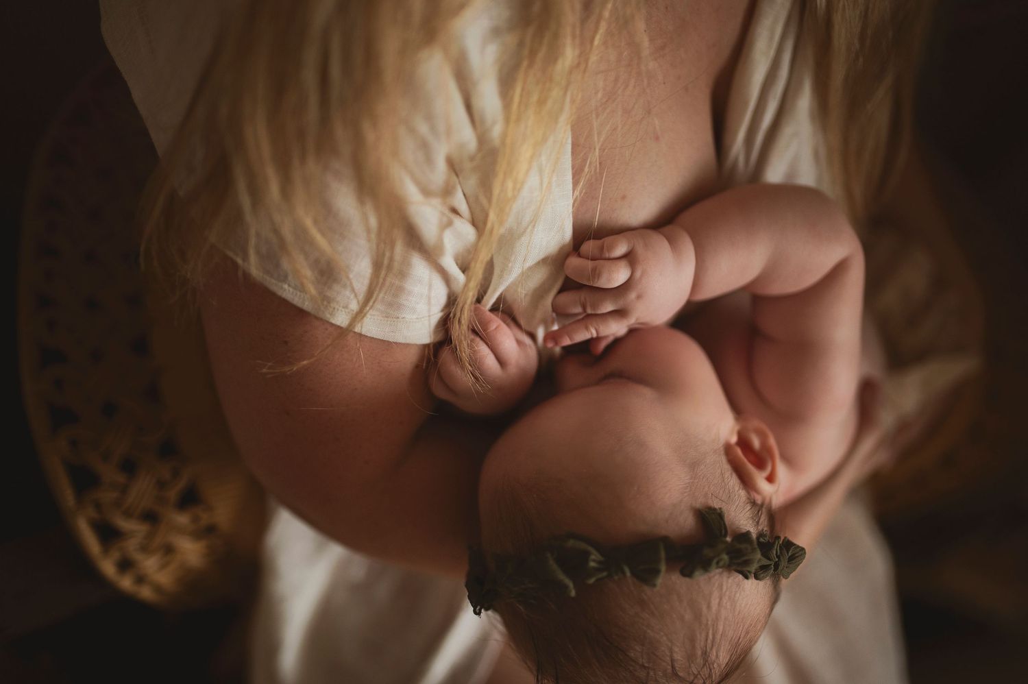 Intimate detail photograph of baby's tiny hand during nursing session.