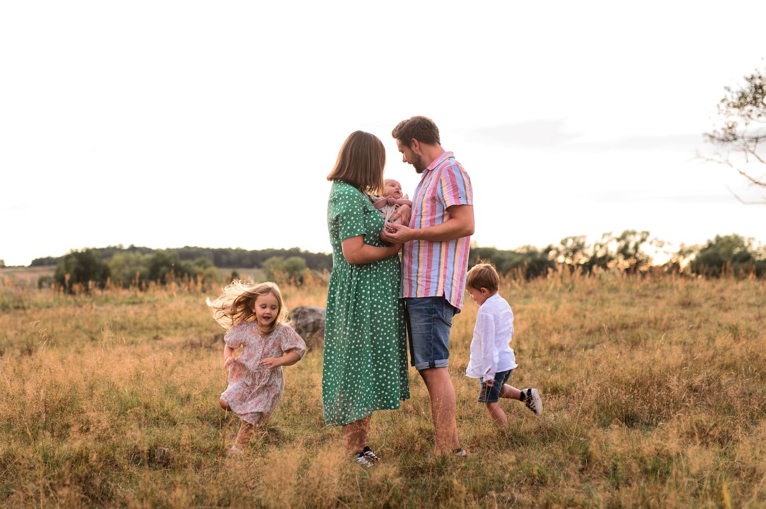 A cheerful summer family scene in a golden field with children playing around.