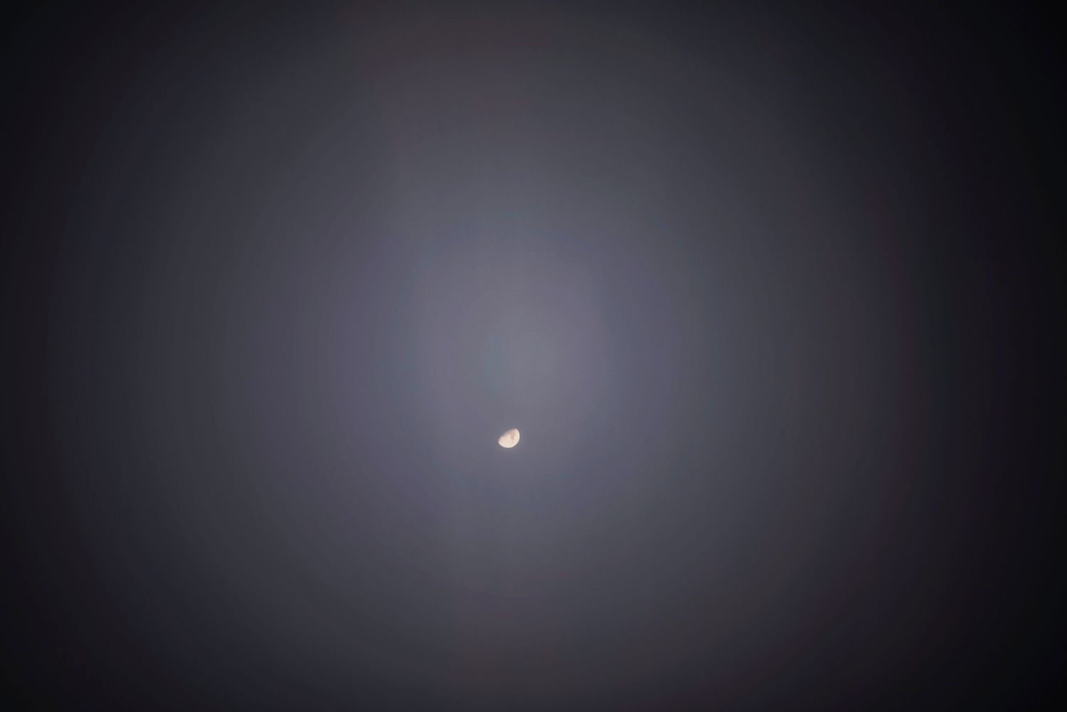 A bright speck of light glows in a misty, dark sky creating a hazy ethereal effect.