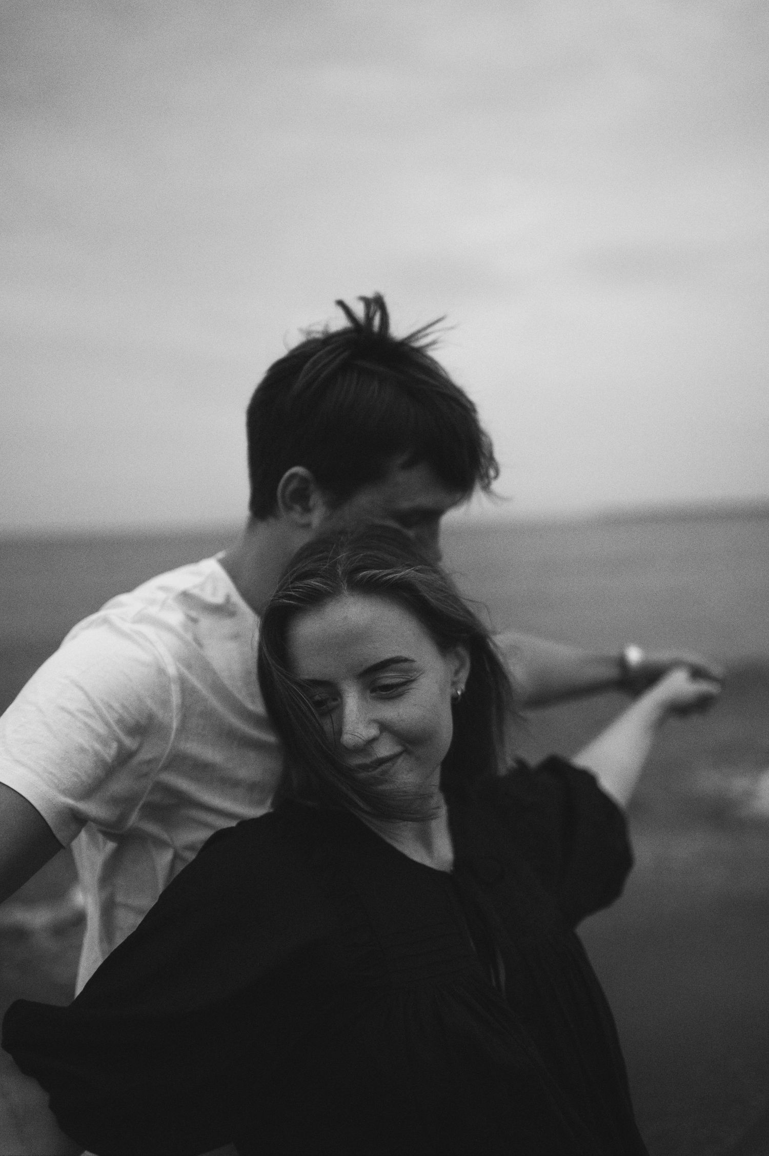 Intimate black and white portrait of couple sharing tender moment by the ocean.