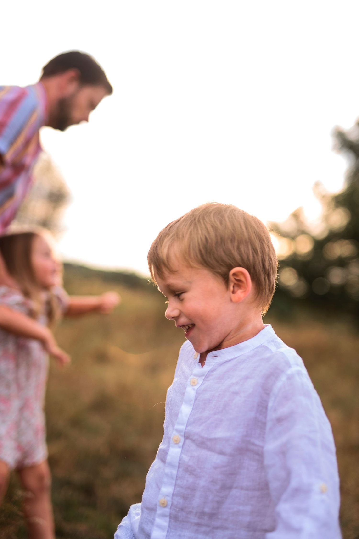 Candid moment of laughter in a sunlit field.
