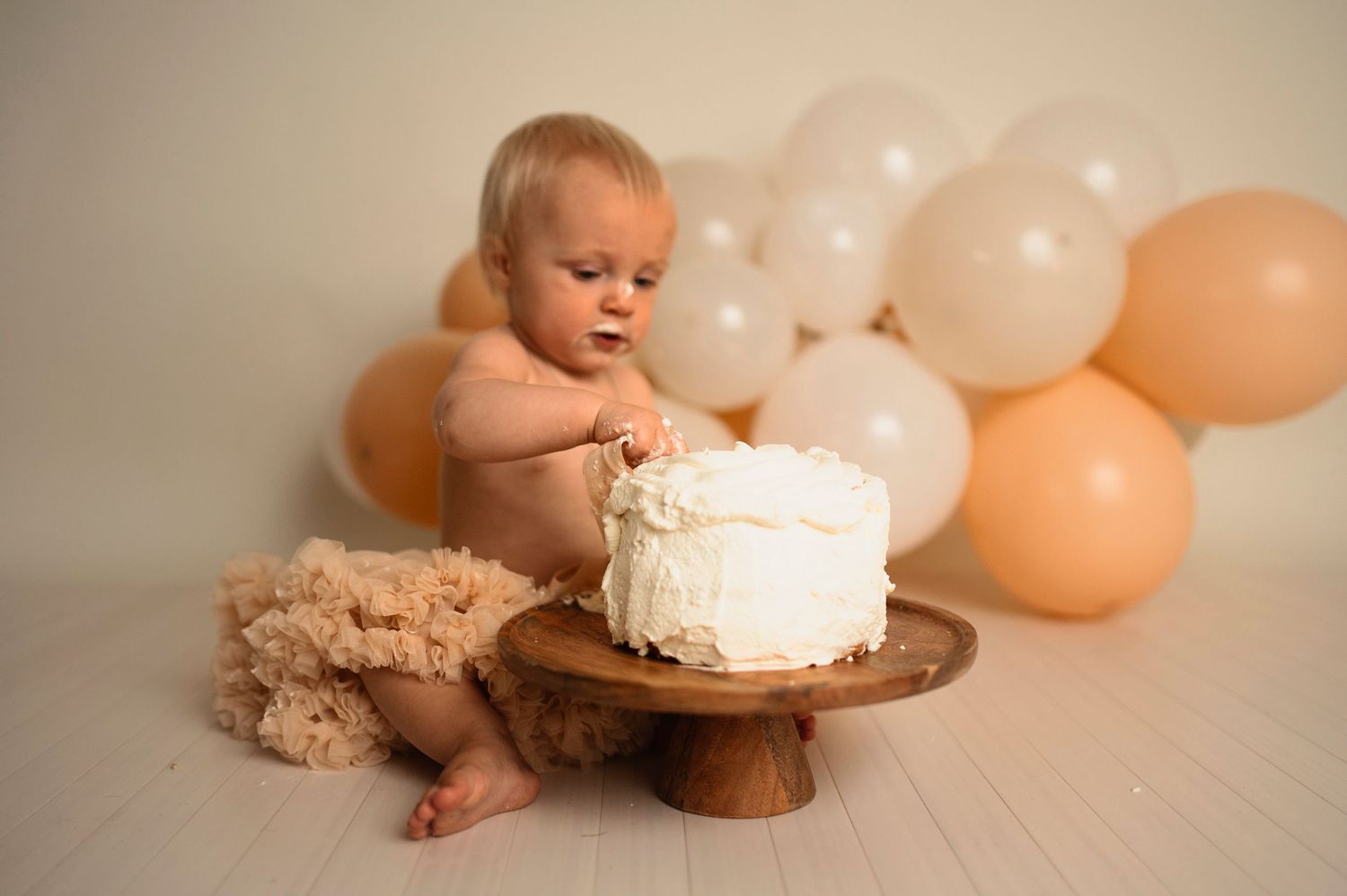 Flicka på sin smash the cake fotografering hos Lovestories By Sara. Flickan har på sig en beige tyllkjol.
