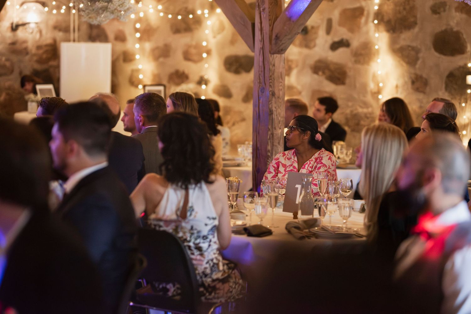 Wedding reception dinner in a rustic stone venue with ambient lighting and decorated tables.