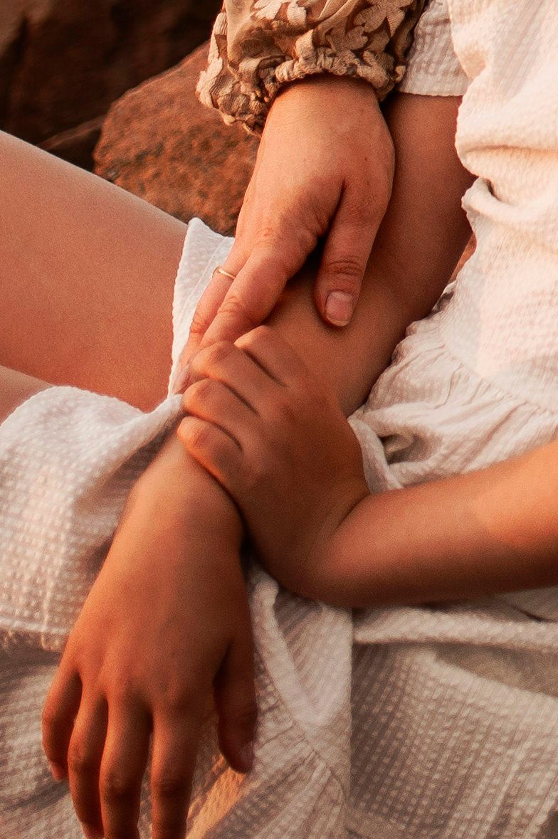 Close-up shot of gentle hands touching on white textured fabric in warm lighting.