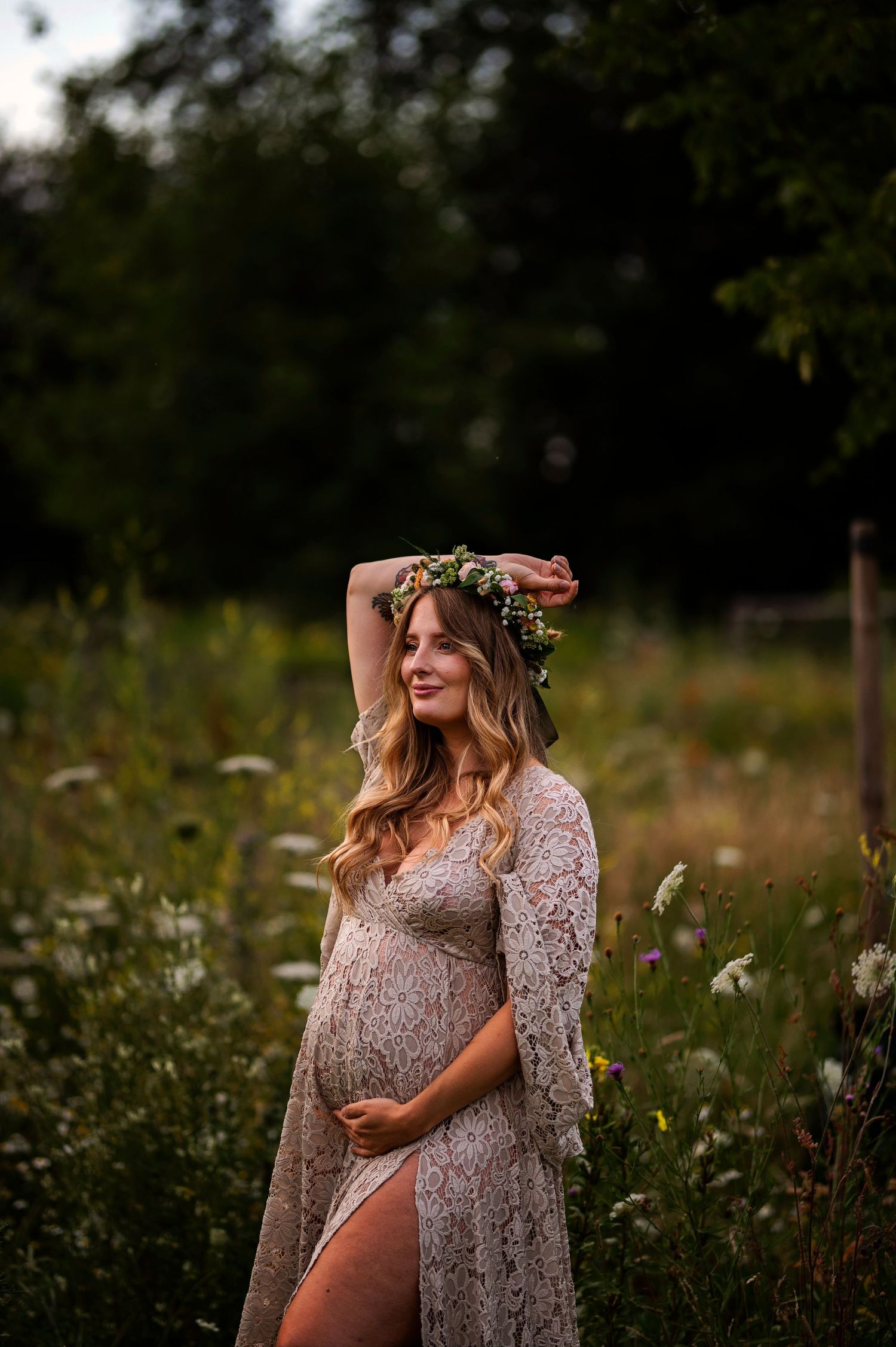 A maternity photoshoot in a wildflower field featuring a lace dress and floral crown at sunset.