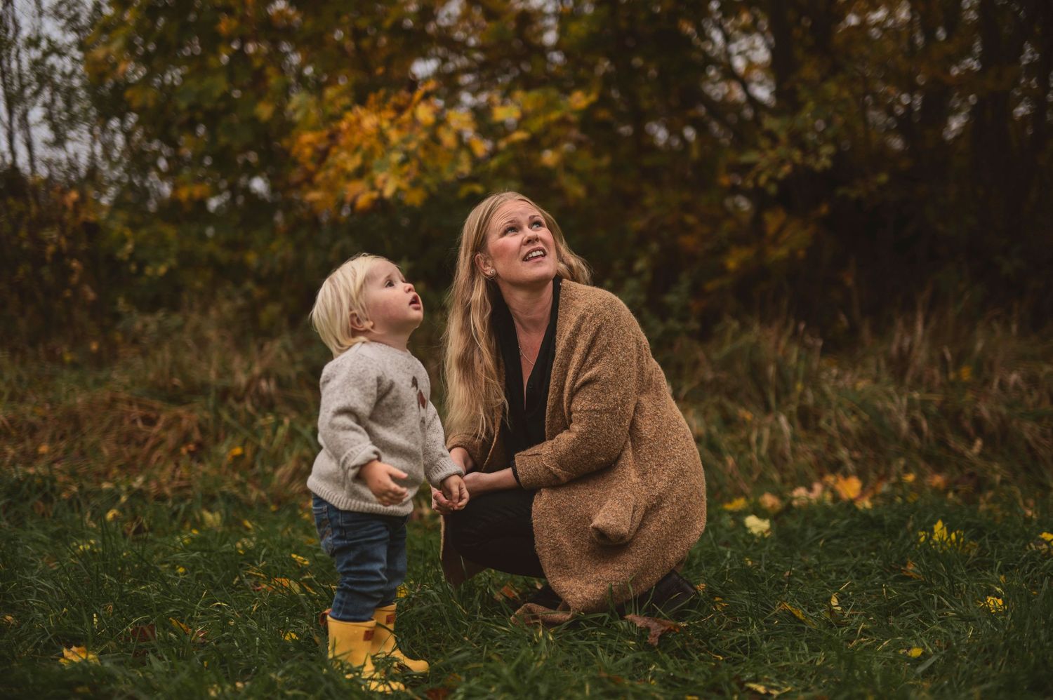 Playful autumn moment outdoors with yellow boots and fallen leaves.