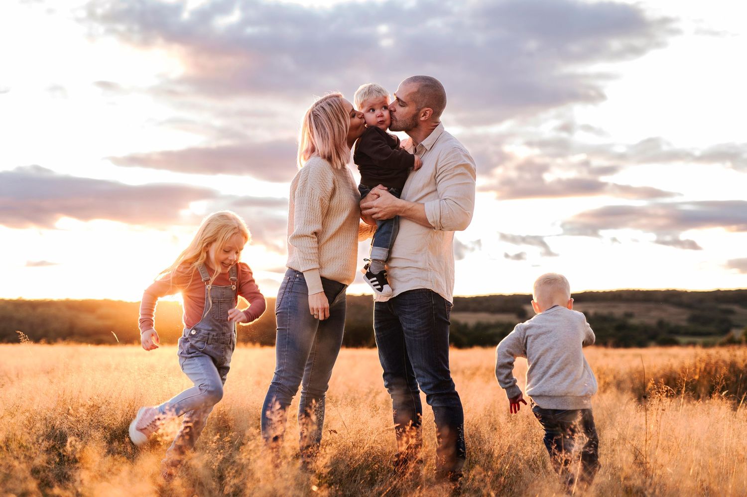 Joyful family moment captured in golden field during sunset.