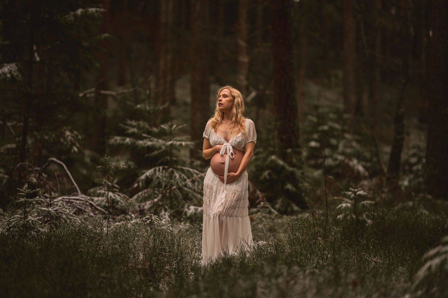 Vacker gravid kvinna på fotografering i en skog med mossa. Fotograf är Lovestories By Sara.