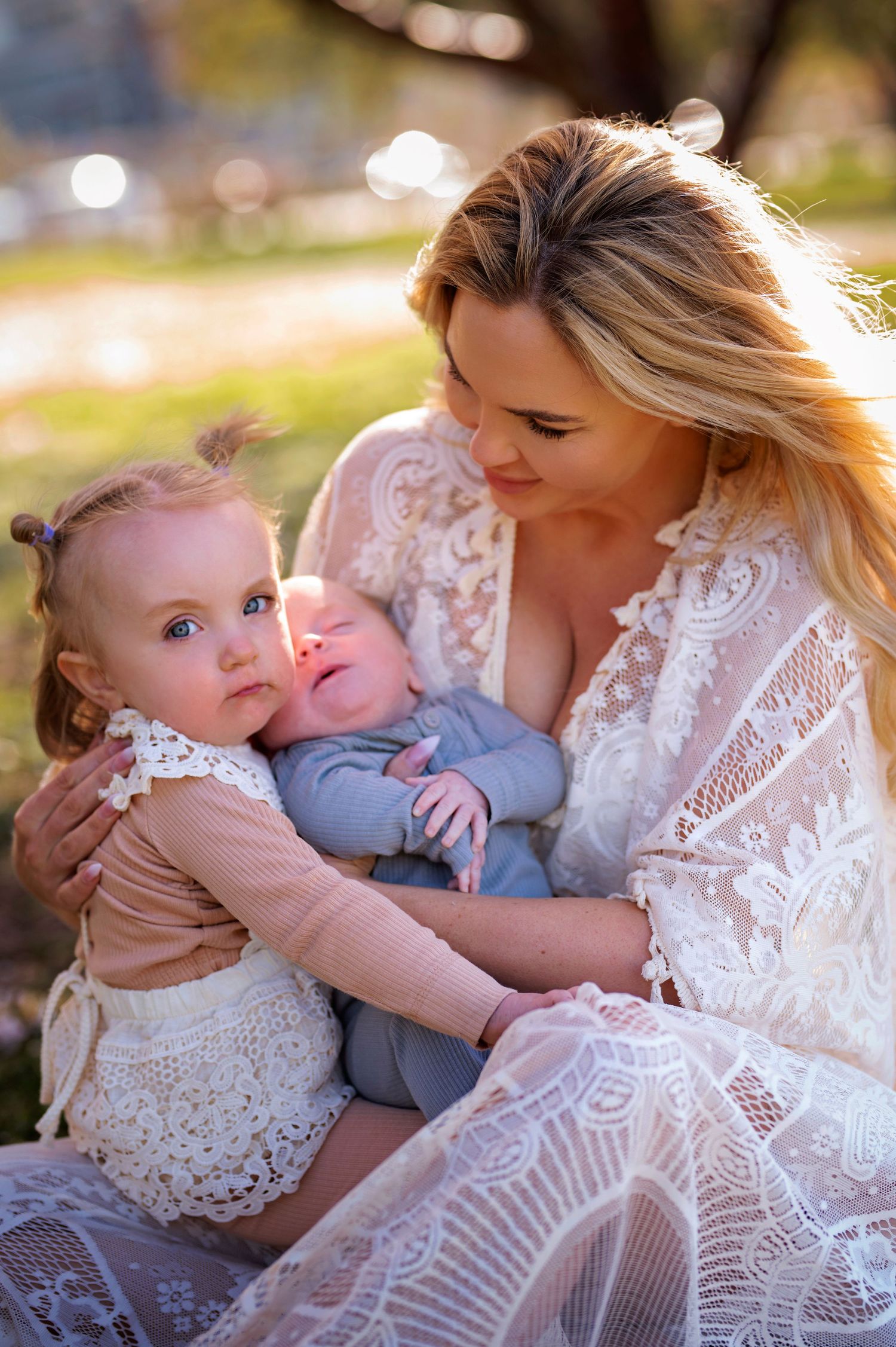 Tender family moment captured outdoors with delicate lace details and soft natural lighting.