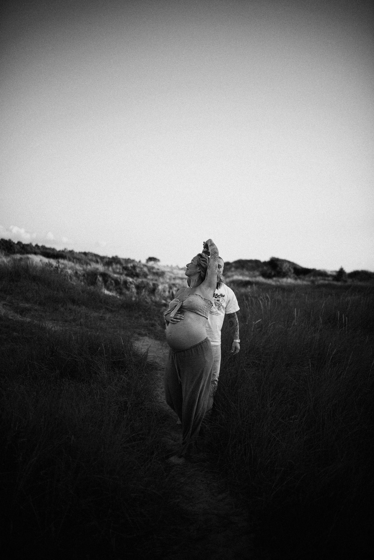 Two figures stroll on a grassy hilltop silhouetted against a moody sky.