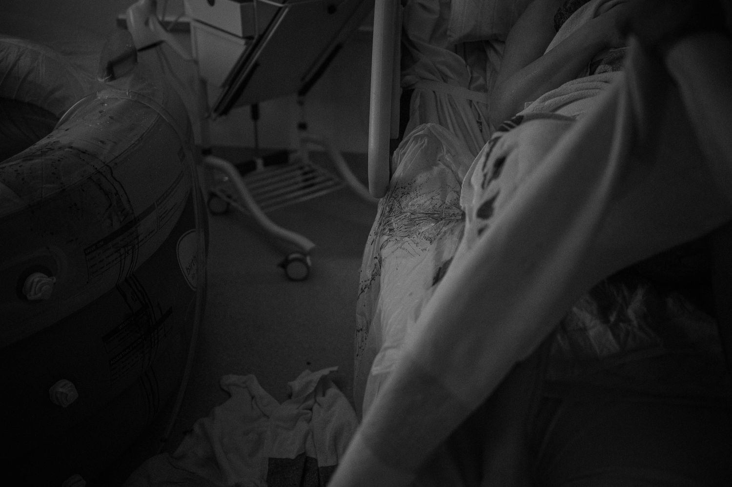 Close-up black and white photo of hands and medical gowns during childbirth.