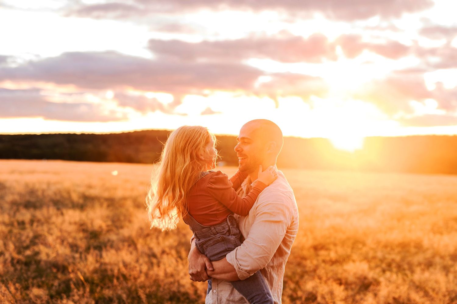 Warm embrace captured in beautiful golden hour lighting in a rural field.