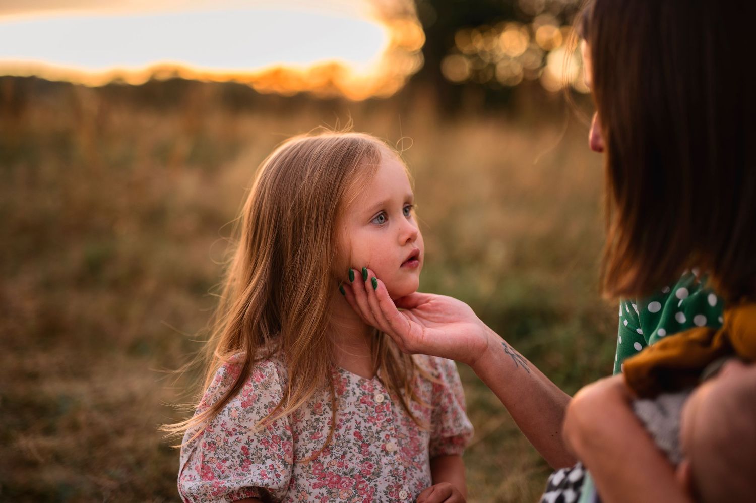 Tender moment between two people in a field during golden hour.