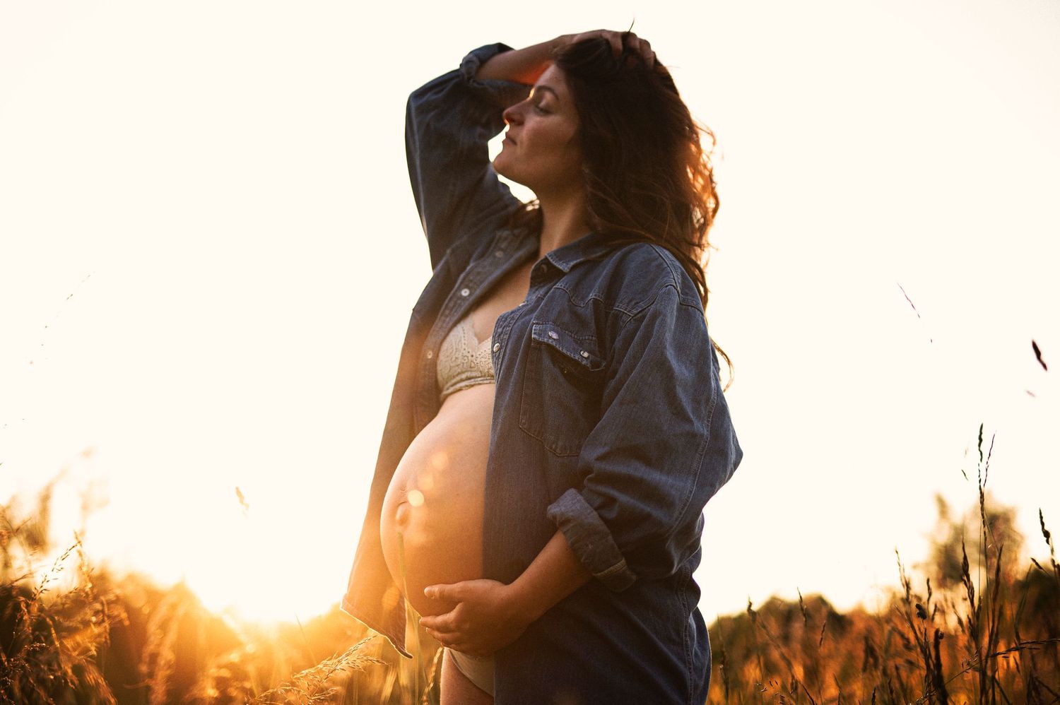 A sunset maternity photo shows a silhouette against warm evening light in tall grass.
