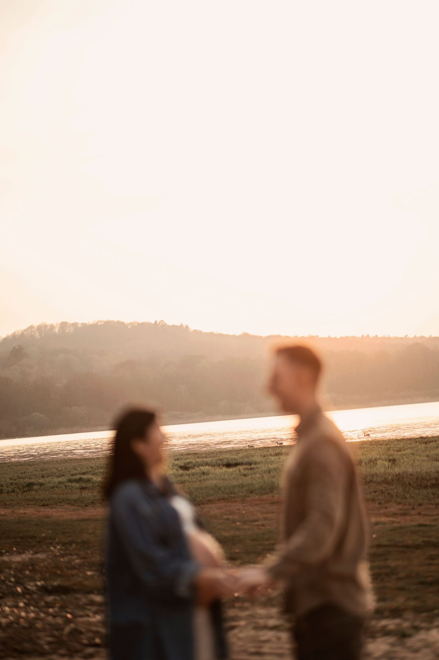Couple silhouetted against a misty sunset landscape walking together on a hill.
