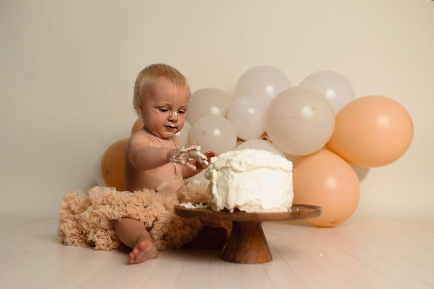 Flicka på sin smash the cake fotografering hos Lovestories By Sara. Flickan har på sig en beige tyllkjol.